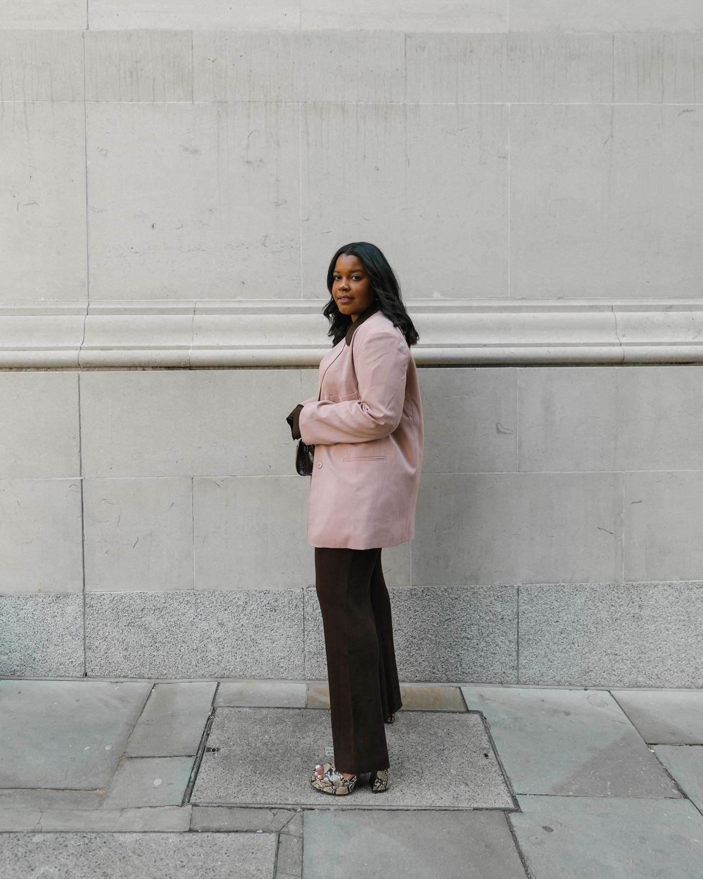 Influencer @styleidealist wears a pink linen blazer with chocolate brown trousers and snake-print heels.