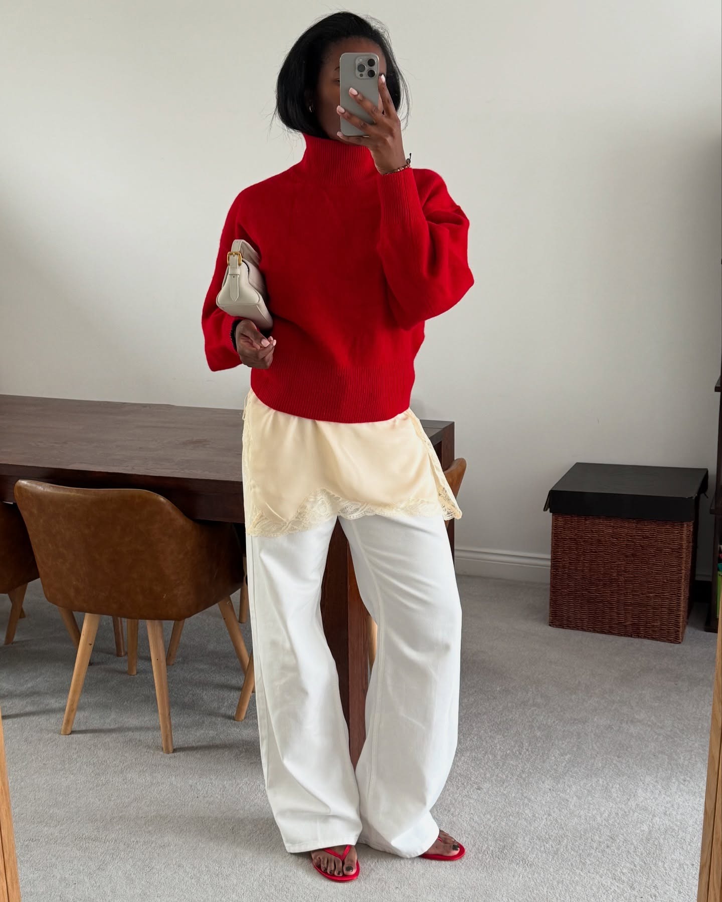 Influencer @nlmarilyn wears a red jumper over a longline top with lace-trim detailing with white trousers and red flip flops.