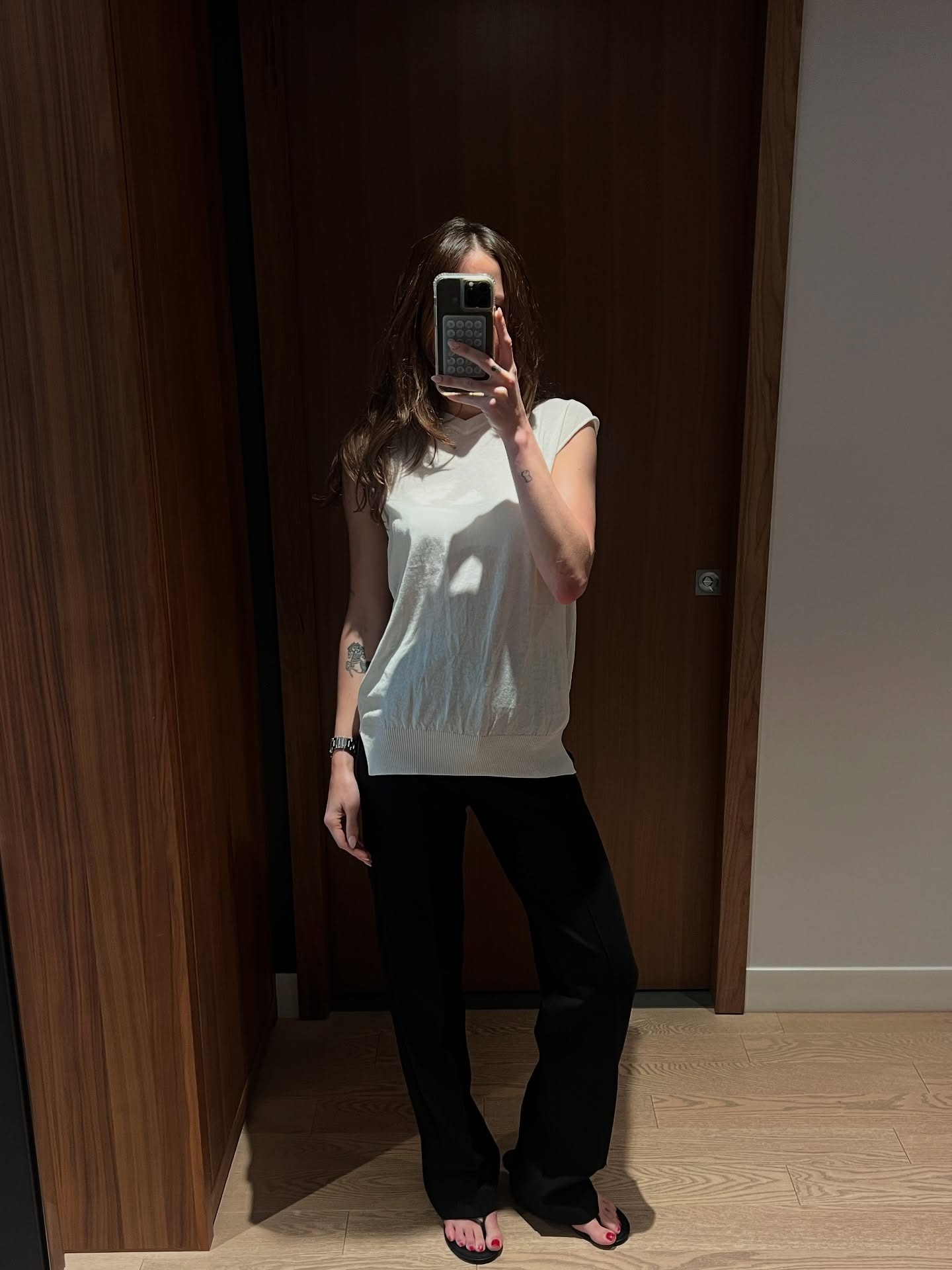 @elizagracehuber wearing a white V-neck top with black trousers.