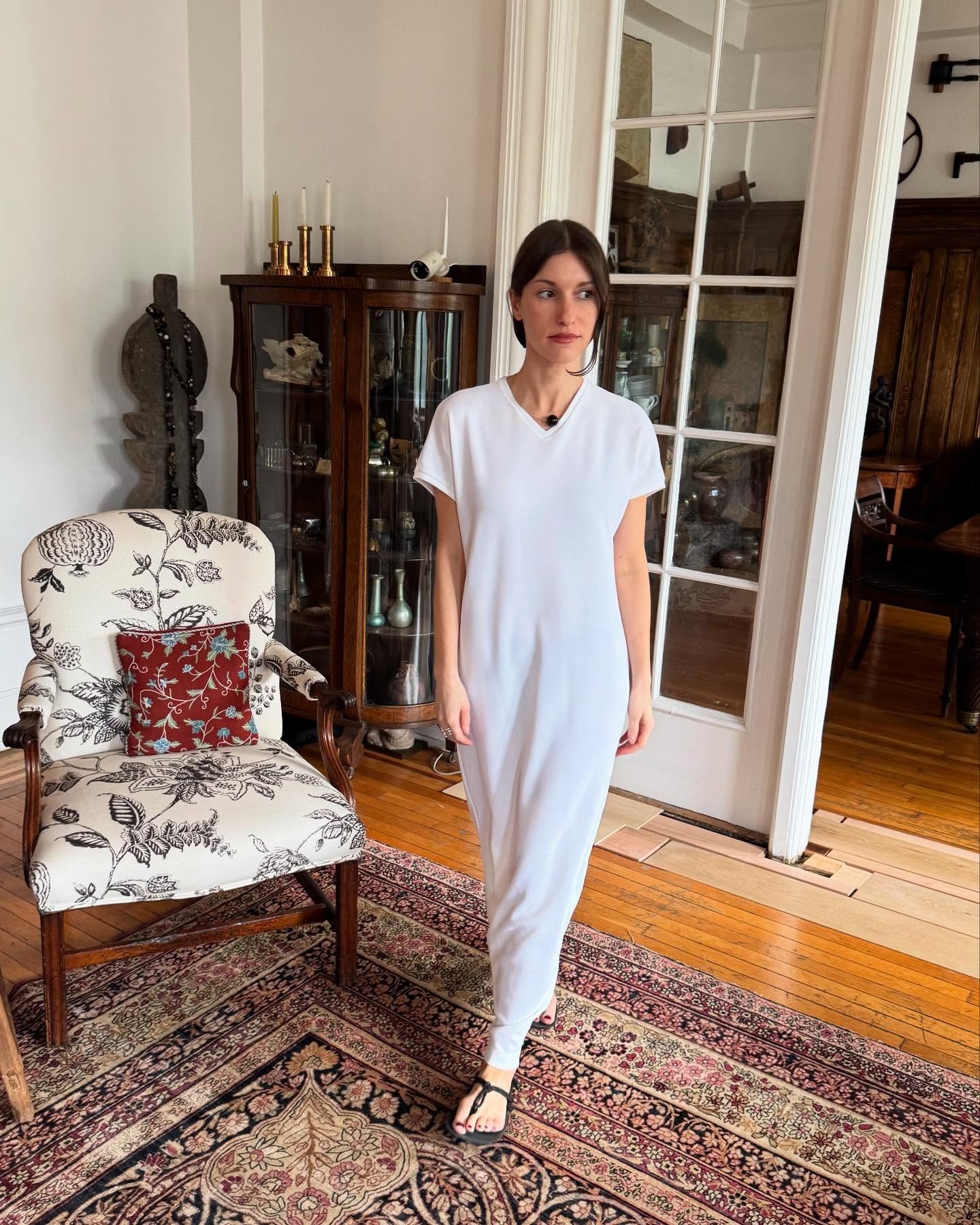 @laurareily___ wearing a white T-shirt dress with sandals.
