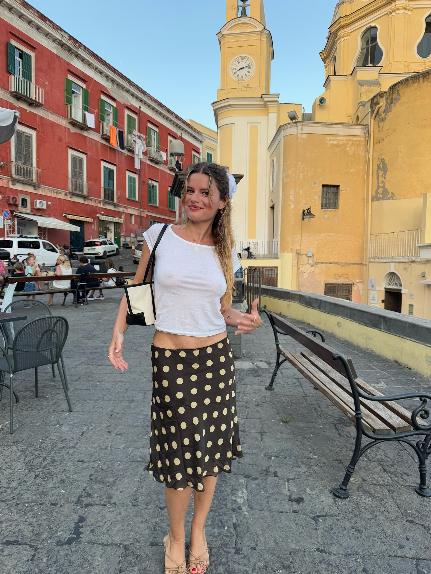 Influencer wearing white t-shirt, dotted slip skirt, and kitten heels while on European vacation.
