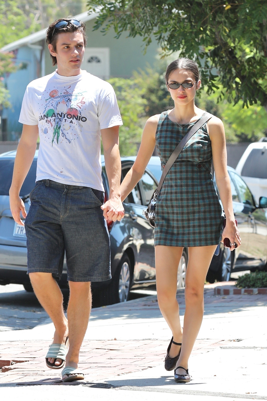Olivia Rodrigo wearing a plaid dress walking with Louis Partridge.