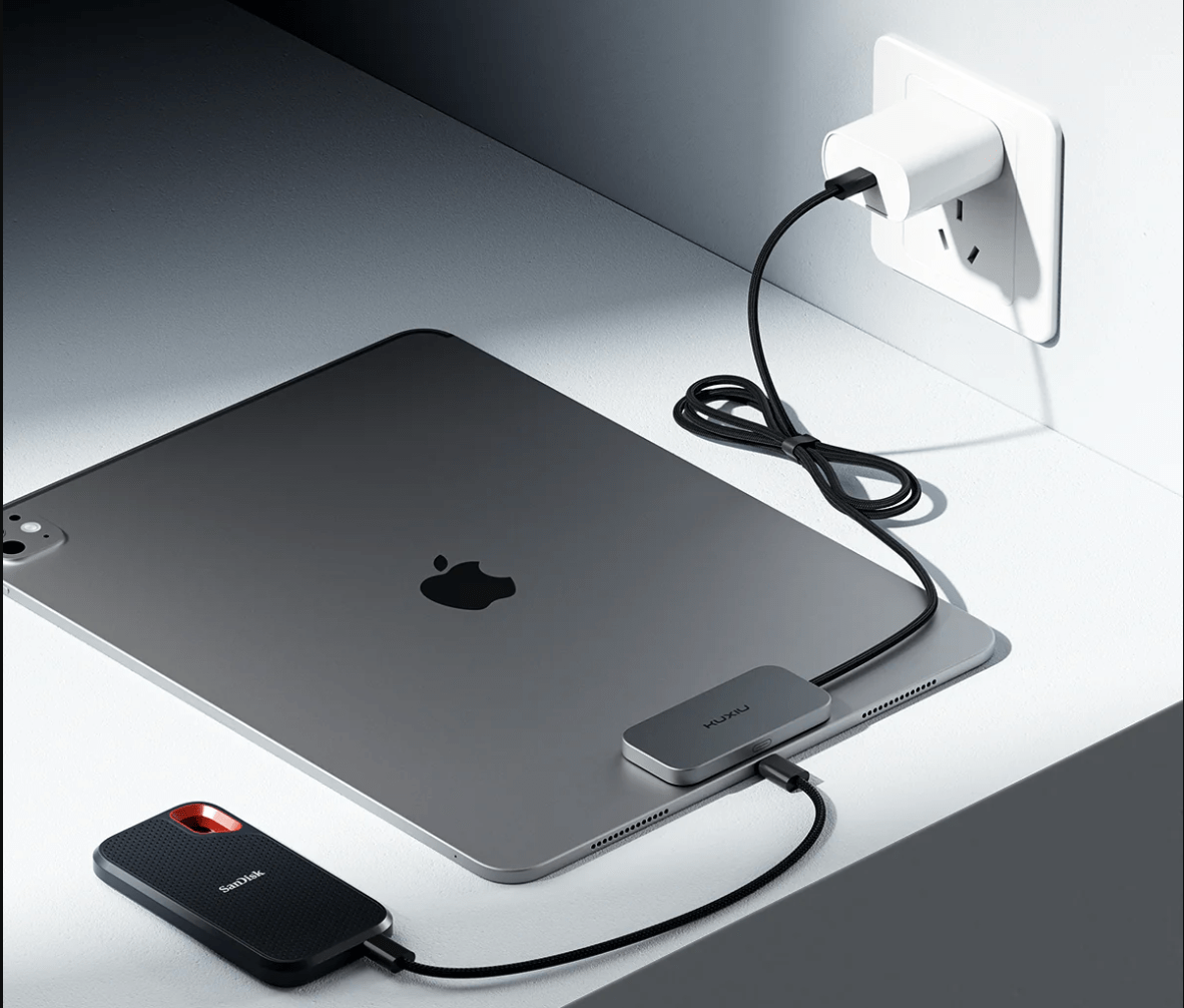 Apple laptop with magnetic attachment with cables leading to the wall and to a phone.
