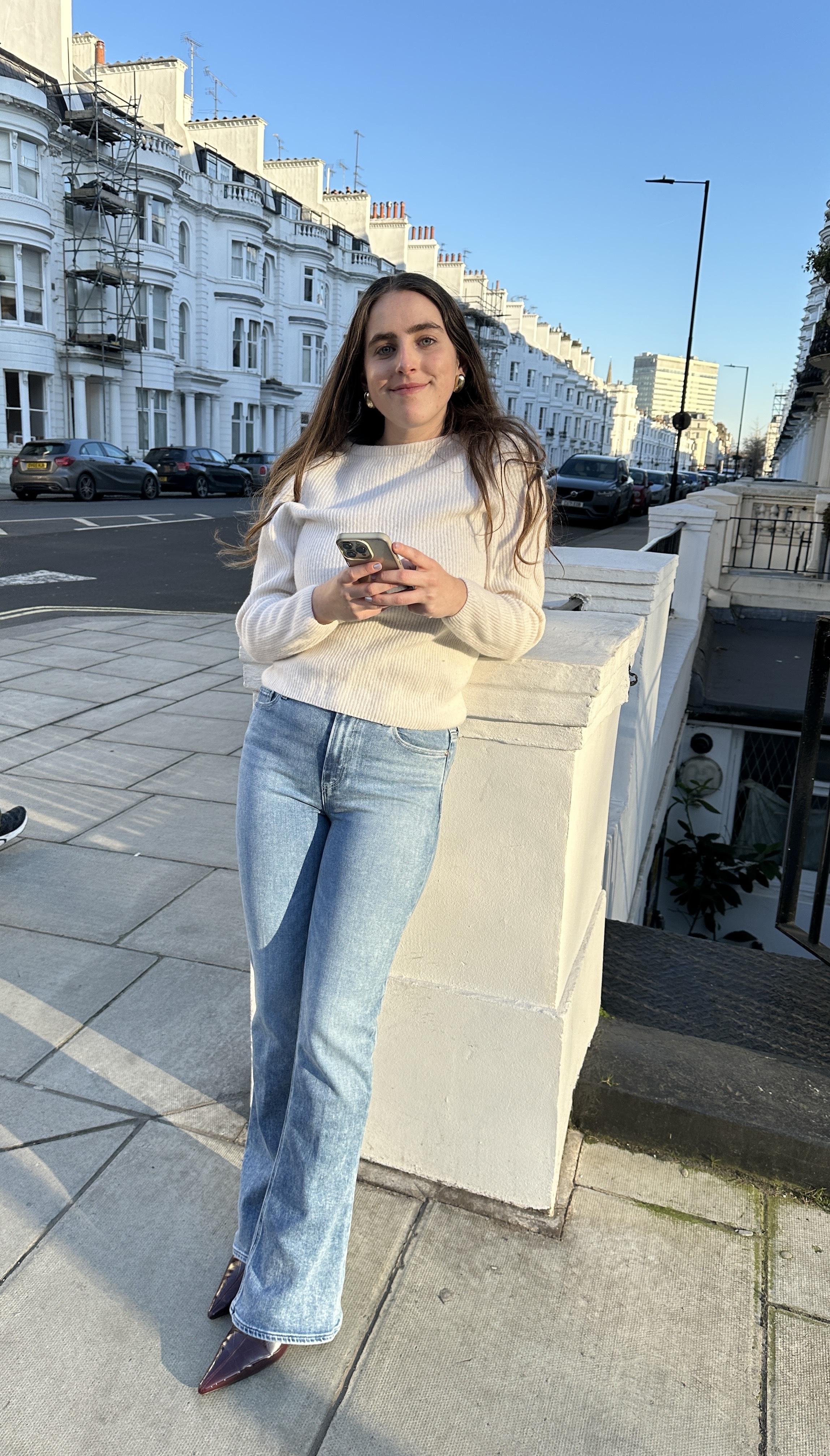 Who What Wear writer @avahgilchrist wears a white jumper with flared jeans and pointed-toe boots.