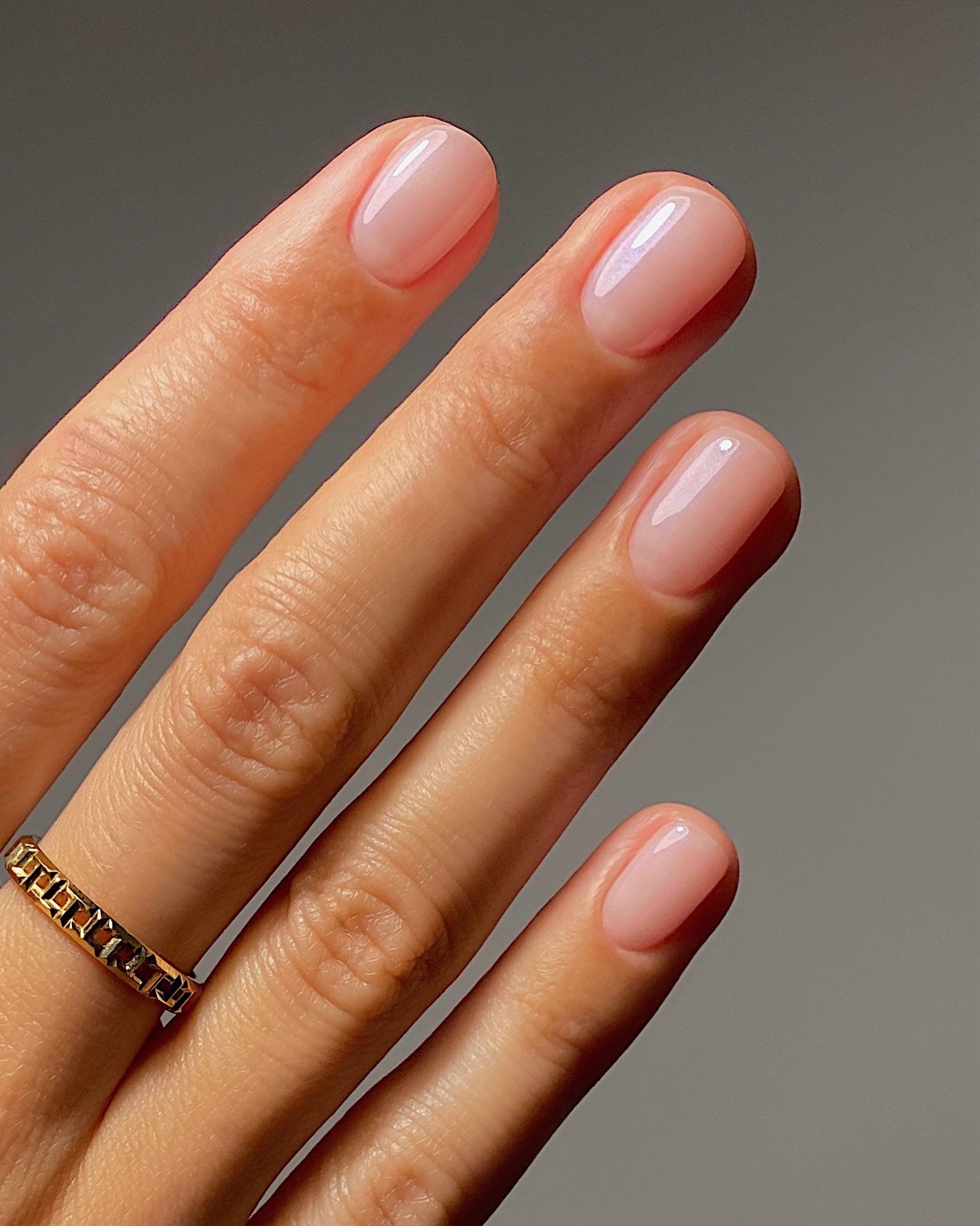 Short, rounded nails with a milky, shimmery polish