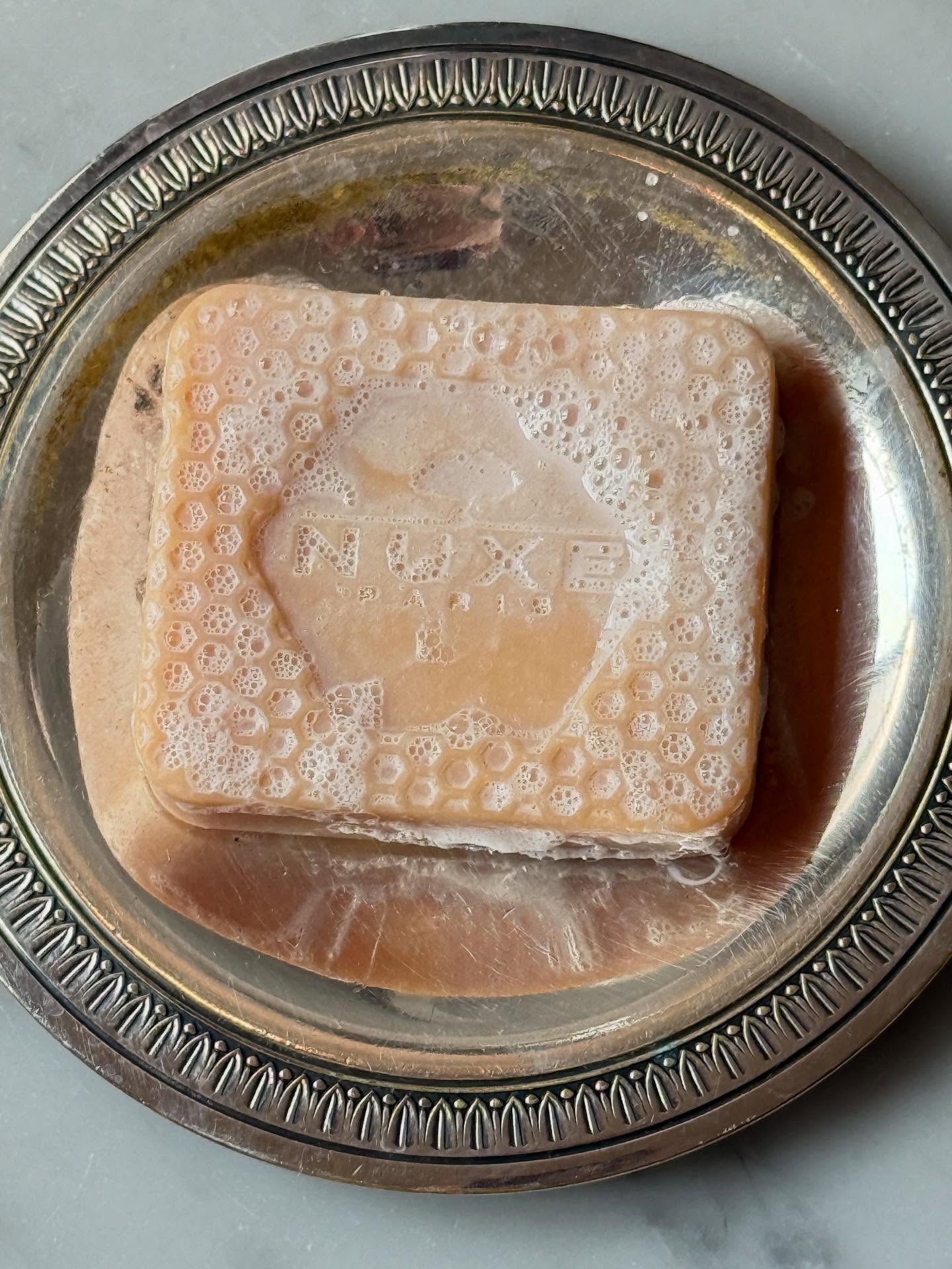 A Nuxe soap bar lathered up on a silver tray