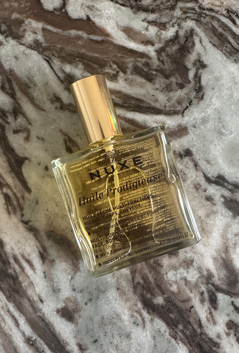 Nuxe Huile Prodigieuse body oil on marble table