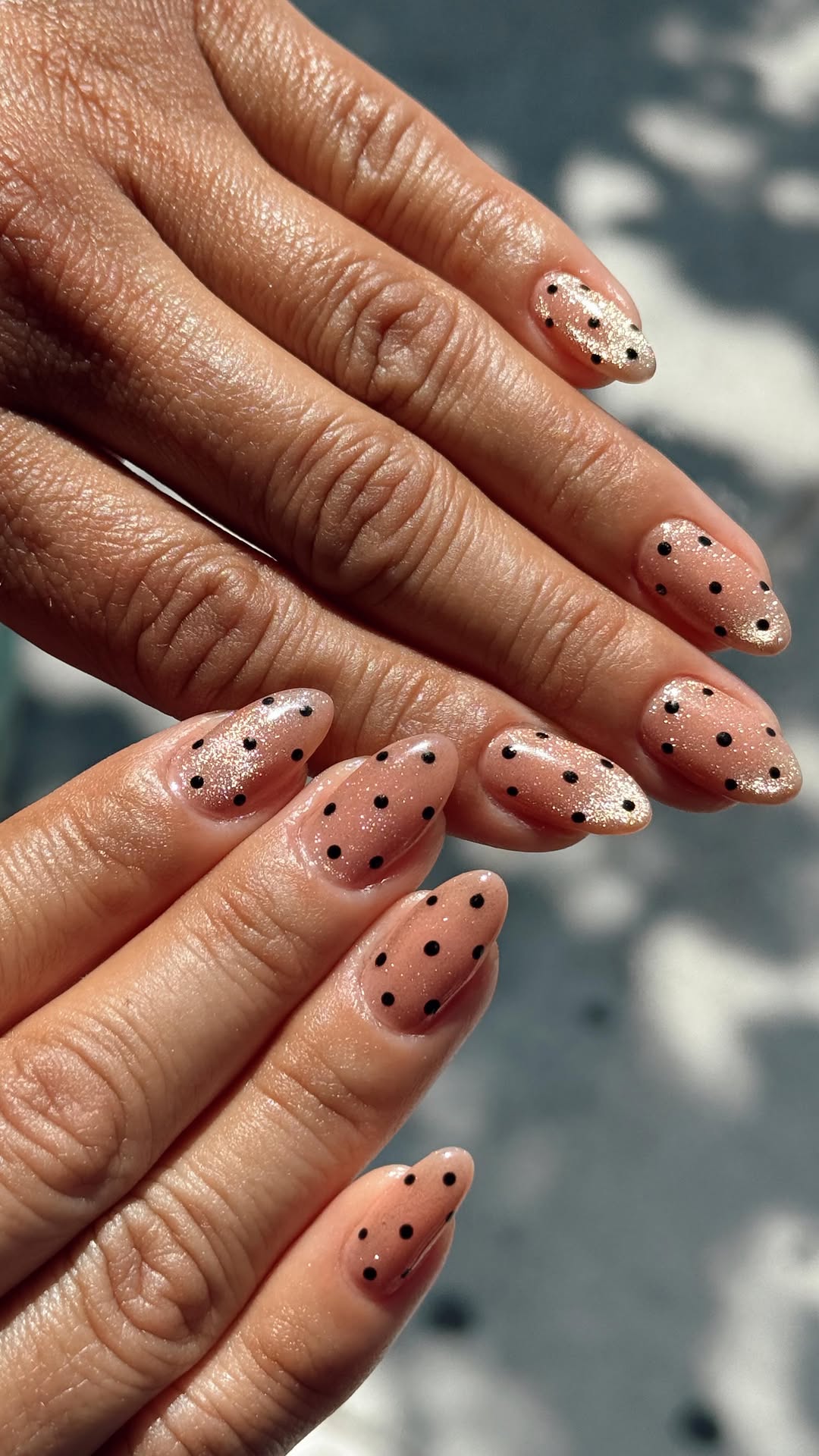 Long almond nails with neutral-toned cat eye polish with black polka dots