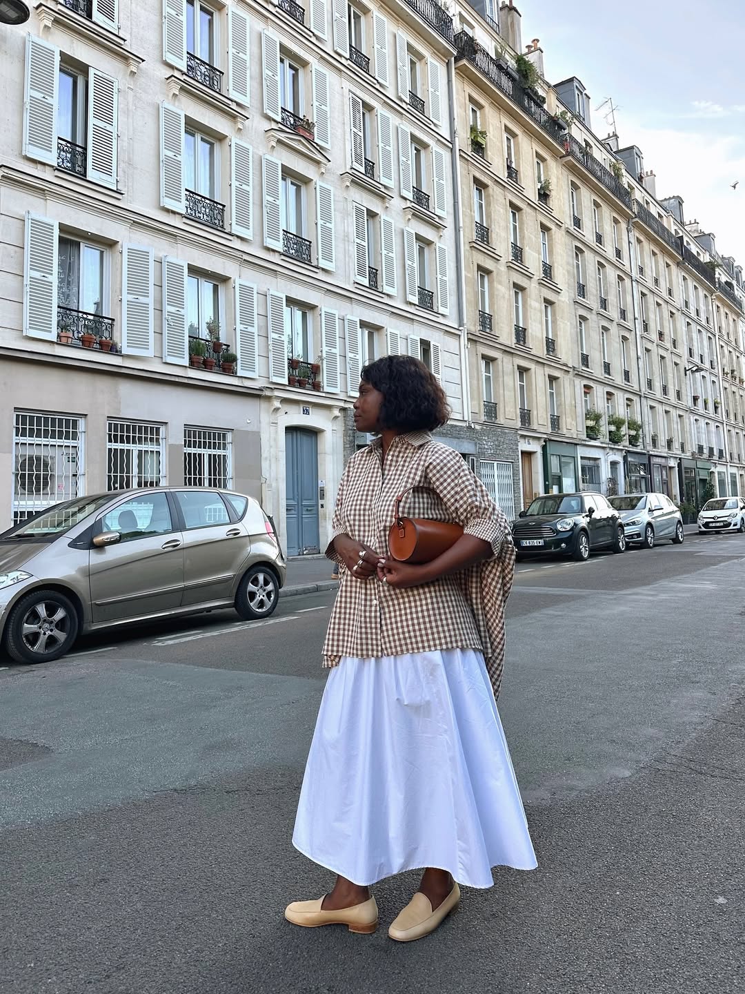 Franny in a white skirt and checkered blouse with loafers