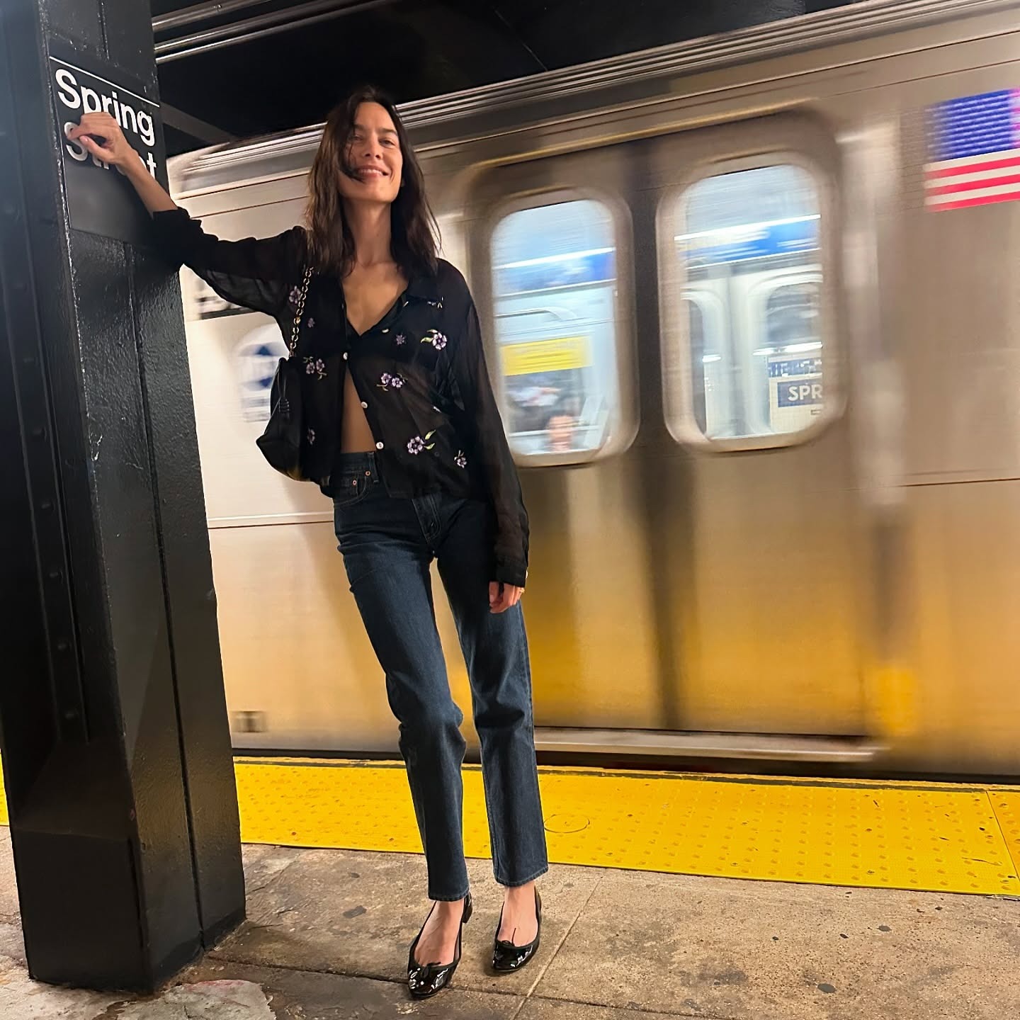 Alexa Chung wears skinny jeans with black patent leather ballet flats and a sheer blouse.