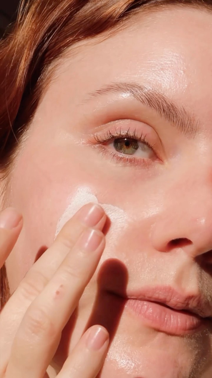 A close up of Emma Hoareau applying skincare to her face