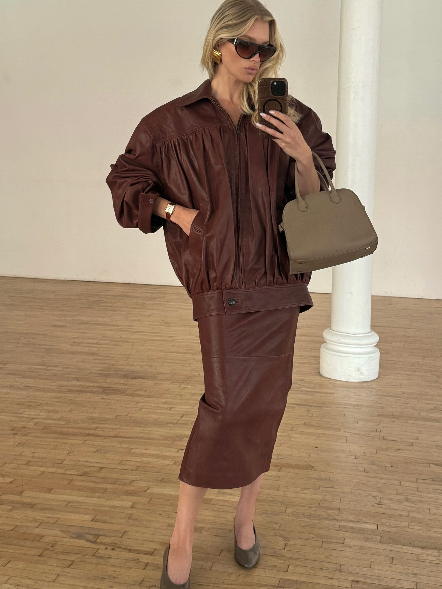 Elsa Hosk takes a mirror selfie wearing a brown leather jacket with a brown leather pencil skirt.