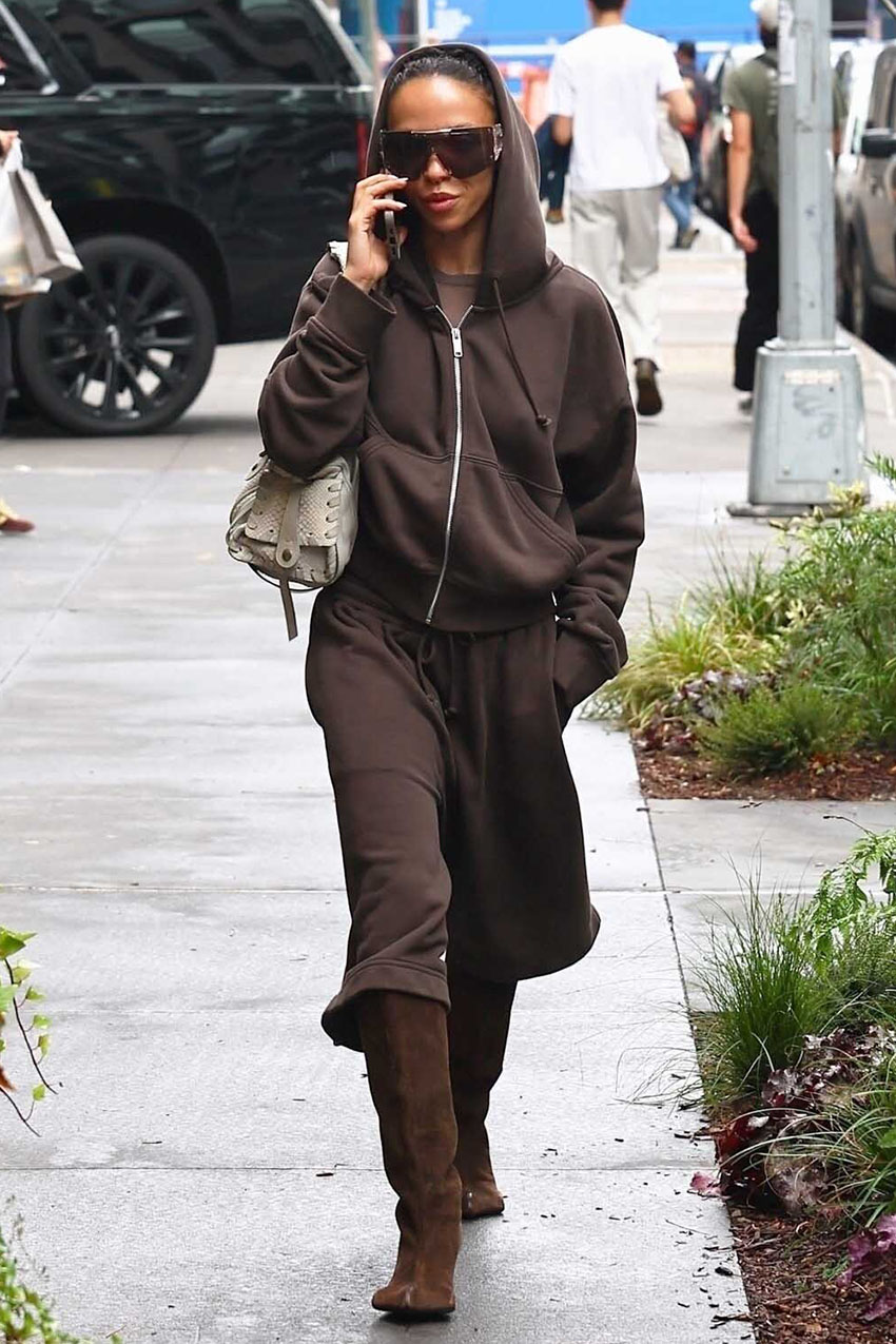 FKA Twigs wearing a brown hoodie, brown Bermuda shorts, brown boots, a gray shoulder bag