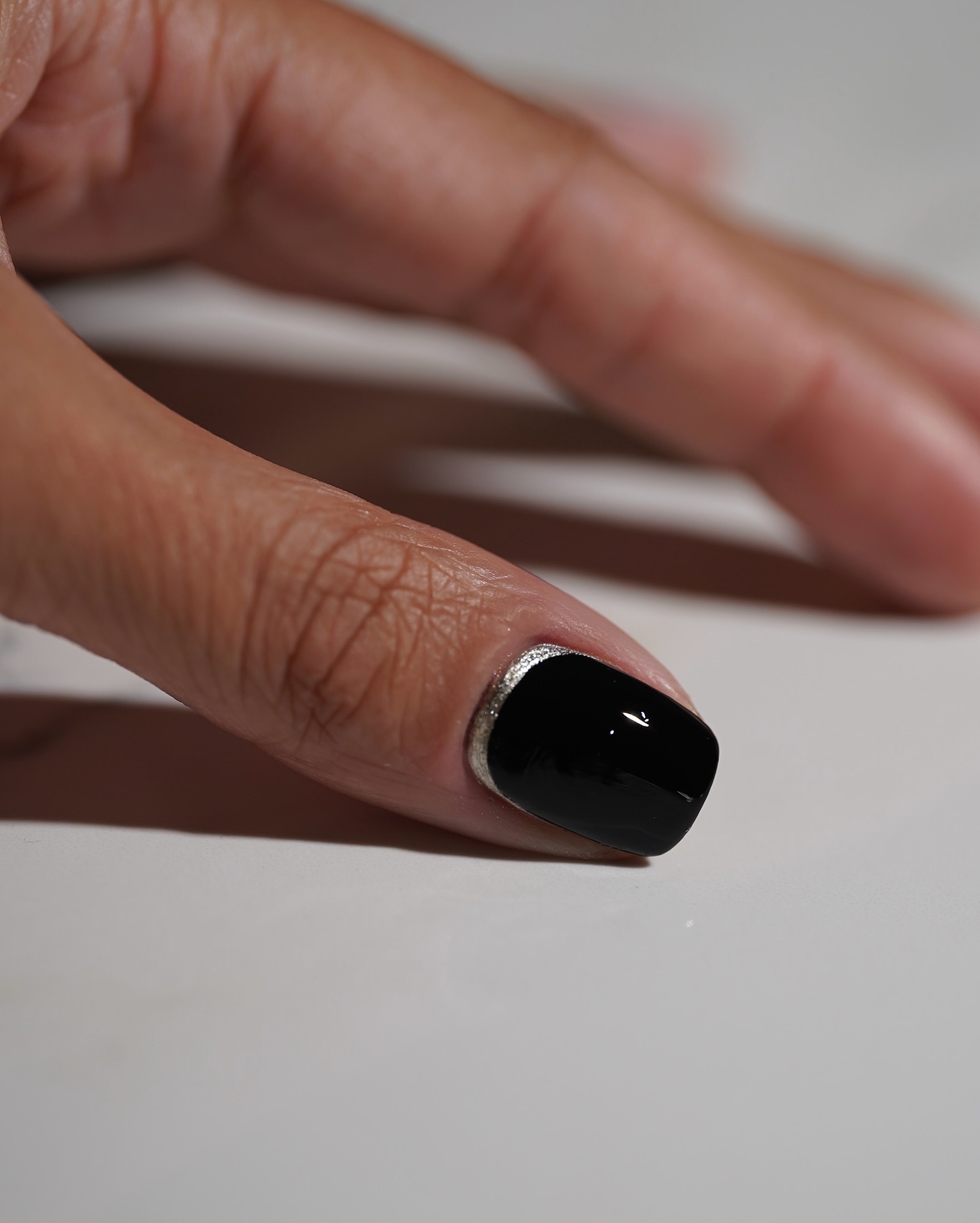 Black nail polish with a silver reverse French tip