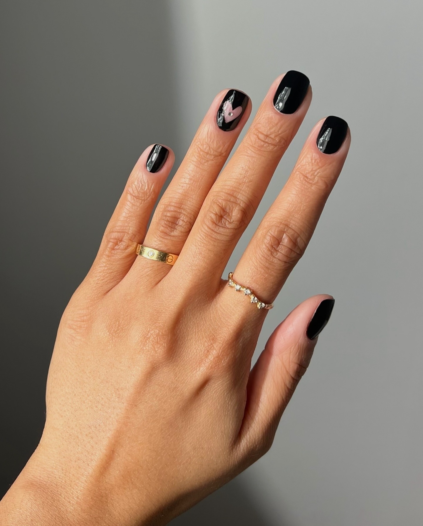 Black nail polish with a clear heart on the ring finger
