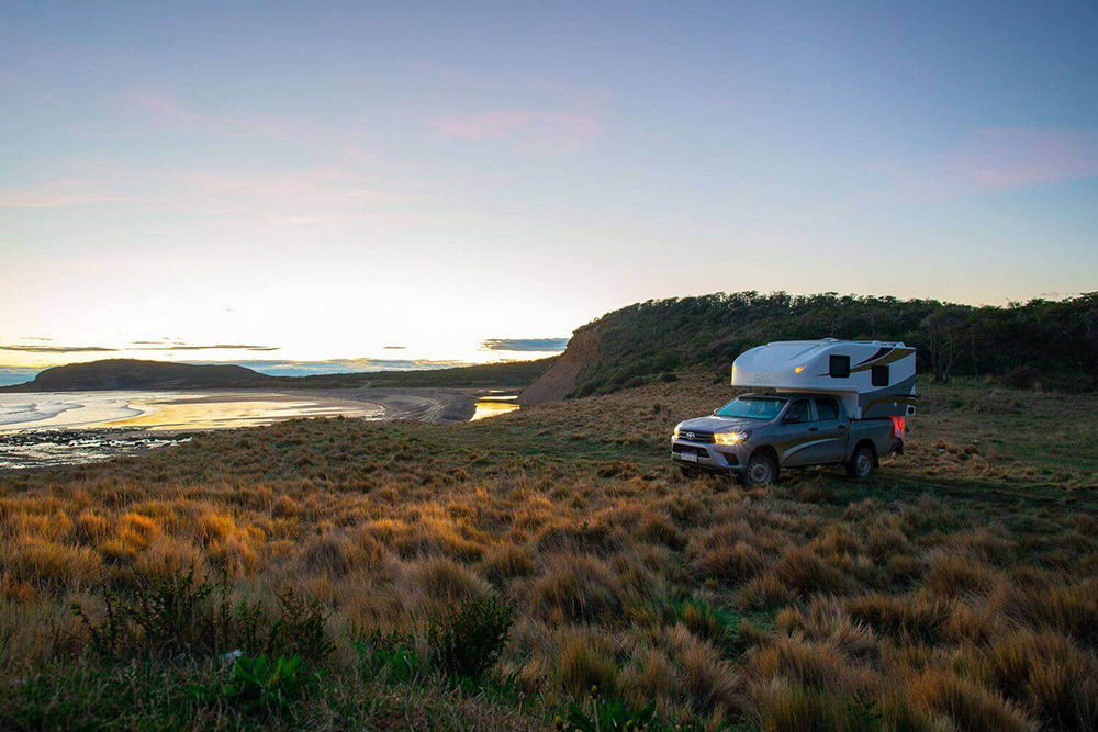 A campervan in the setting sun next to a lake in Patagonia