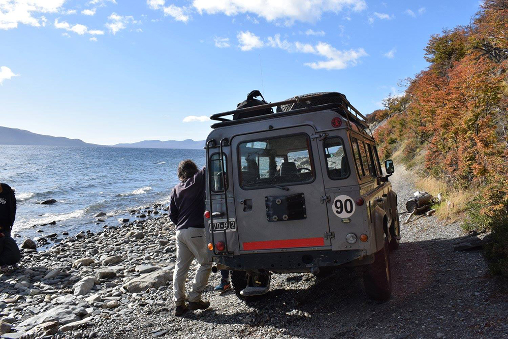 A man stands beside a 4x4 near a lake