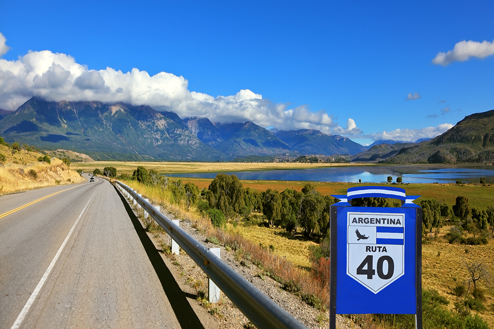 A ruta 40 road sign along a straight road in Patagonia with mountains in the distance