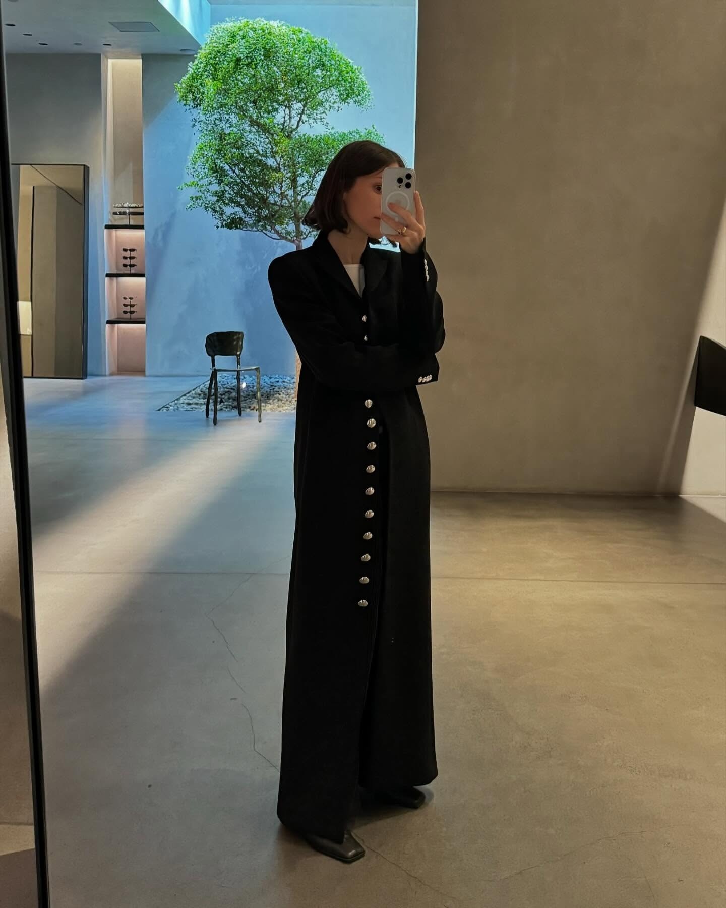 Laura wears a long black coat.