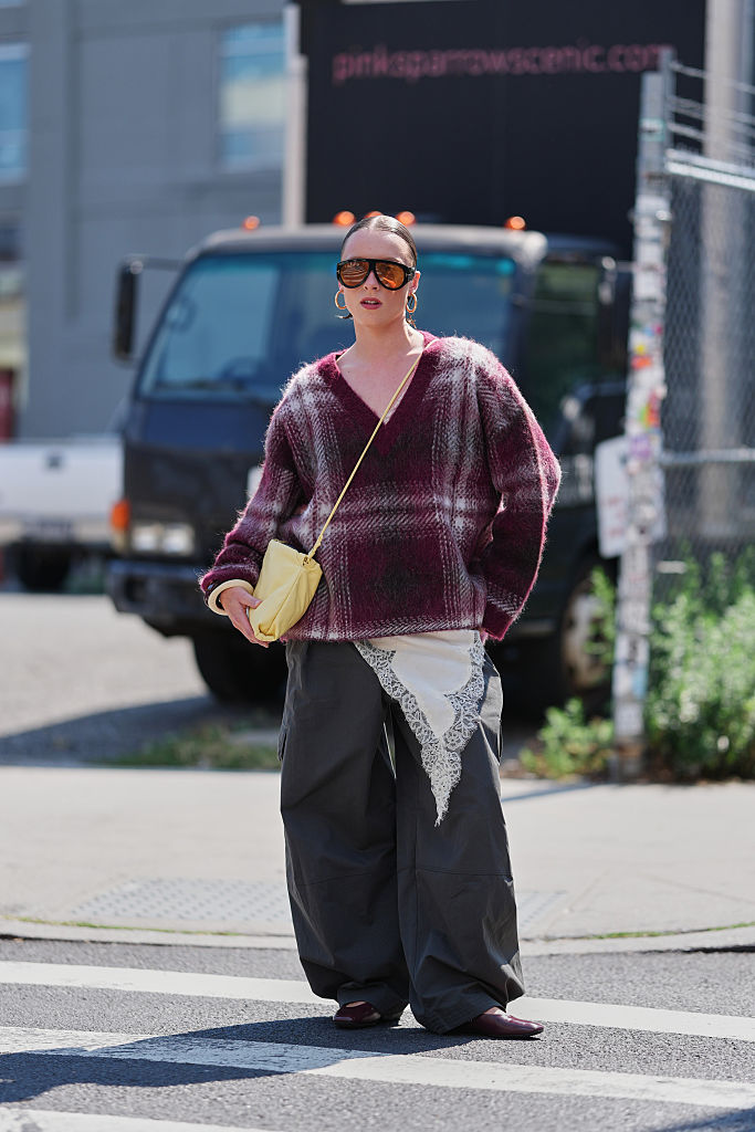 A guest wearing a burgundy COS cashmere jumper and grey trousers at fashion week.