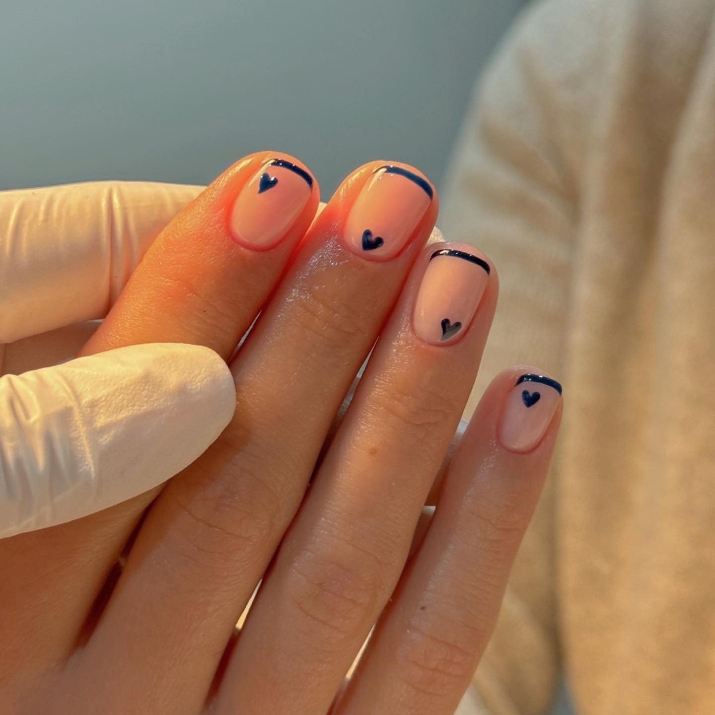 A navy French tip manicure with navy hearts