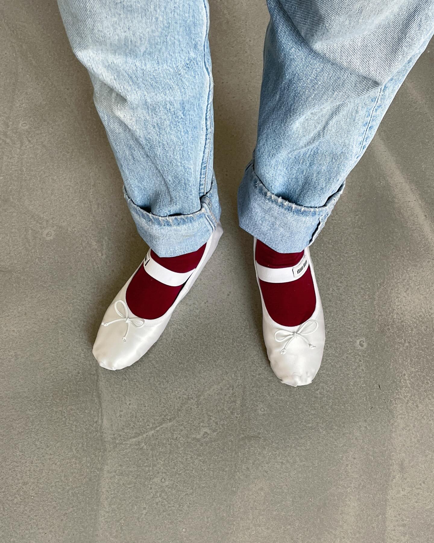 @annelauremais wears a pair of white Miu Miu satin ballet flats with burgundy socks and blye jeans