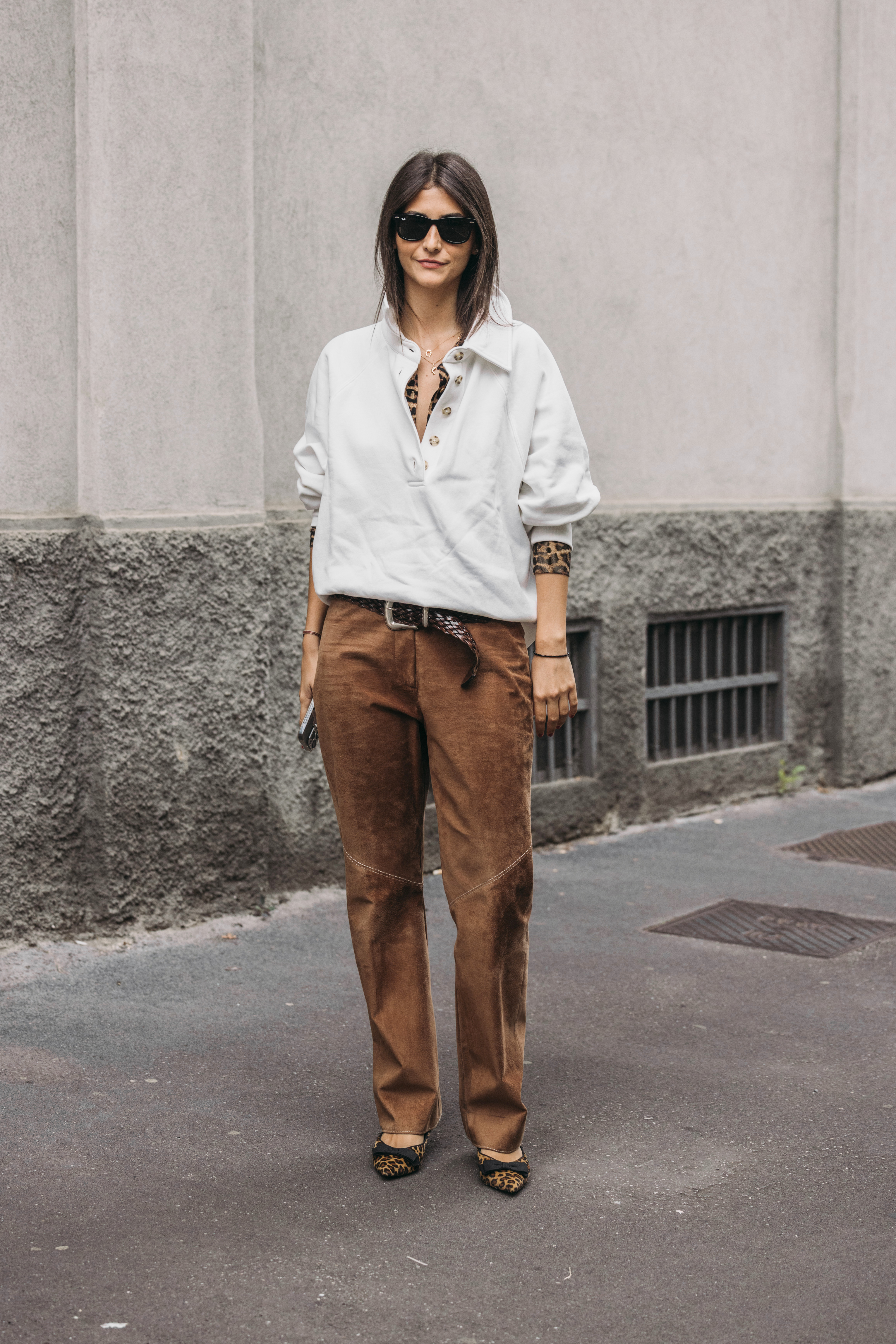 A woman wears brown pants, leopard heels, a belt, and a polo sweater.