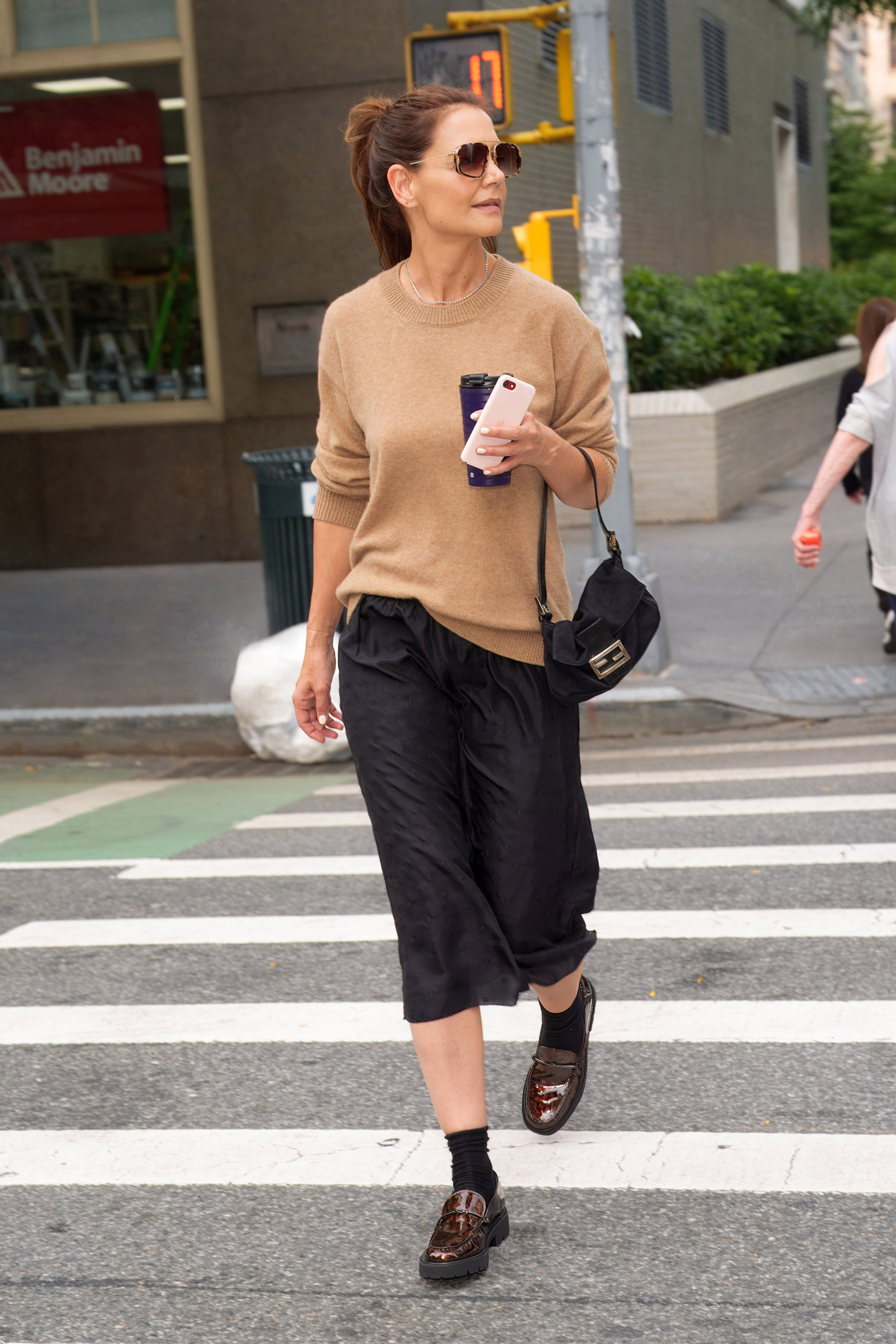 Katie Holmes wears a beige jumper with a midi skirt and tortoise loafers.