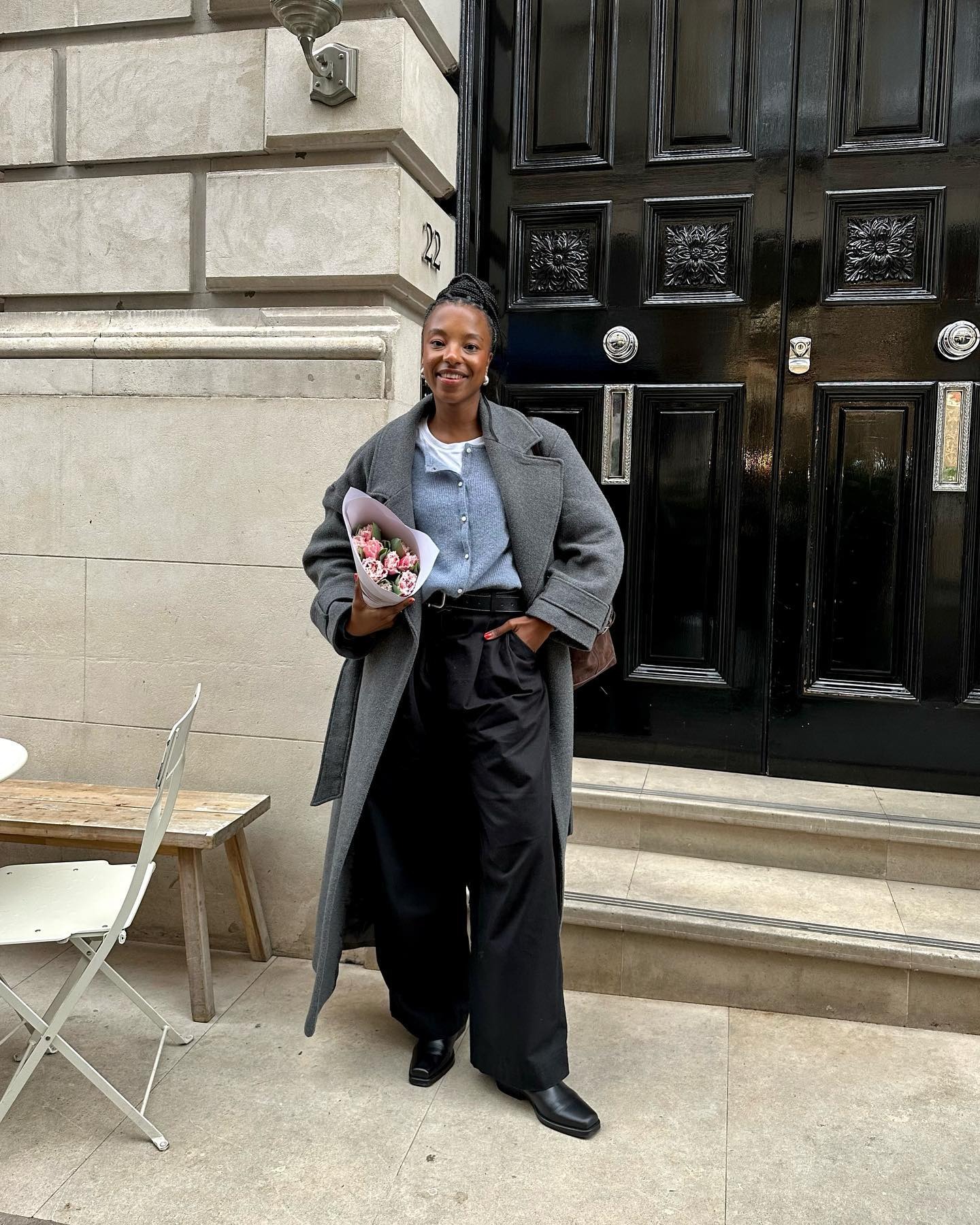 Influencer wears a blue cardigan with trousers and a grey coat.