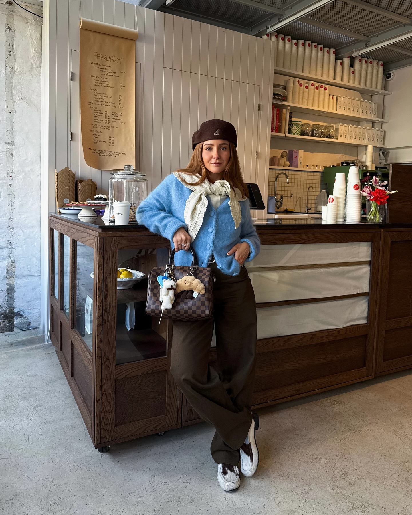 Influencer wears a blue cardigan with brown jeans and loafers.