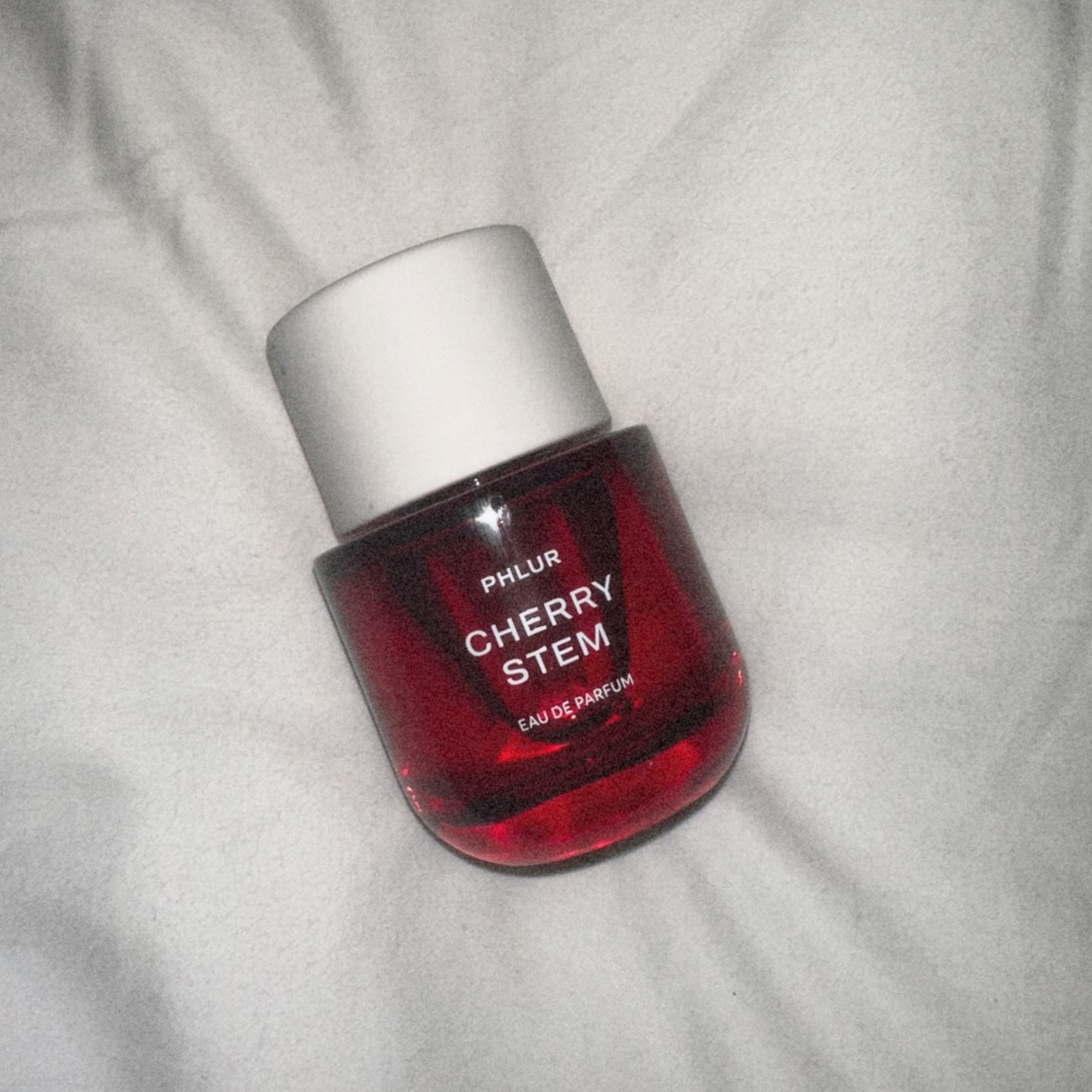Bottle of Phlur&#039;s Cherry Stem Eau de Parfum on a white sheet.