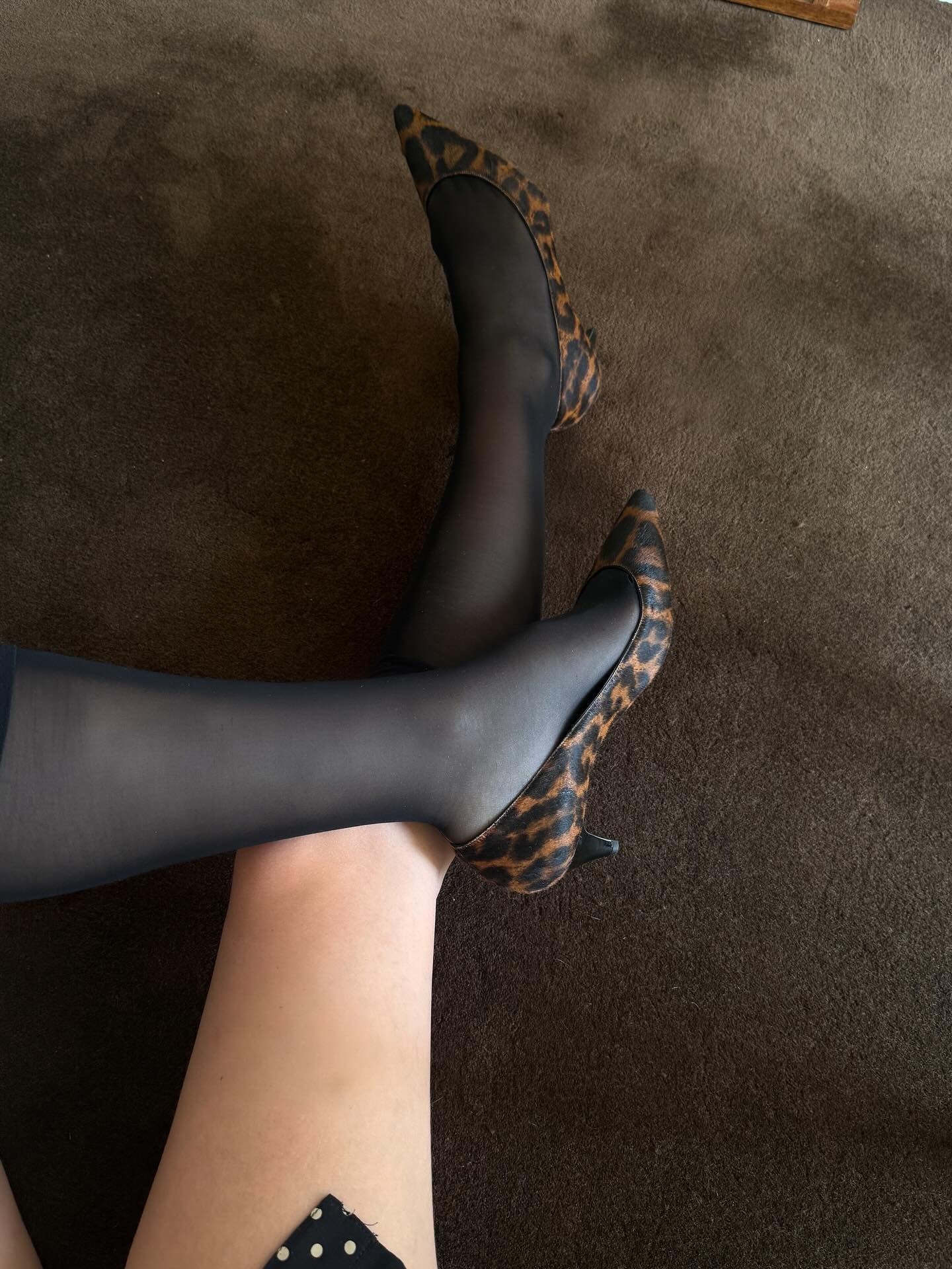 Christie wears leopard pumps with sheer black socks.