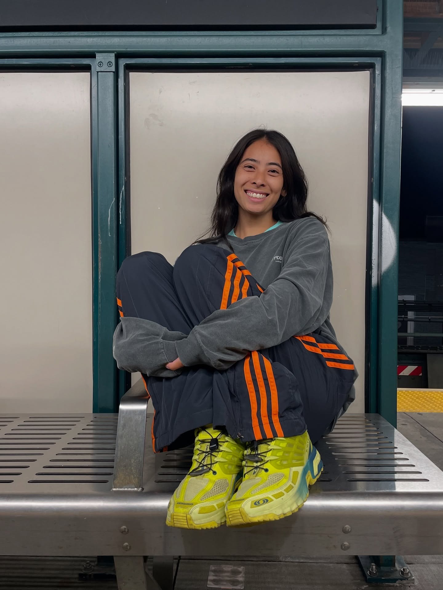 Influencer wearing track pants with a longsleeve tee and neon yellow sneakers