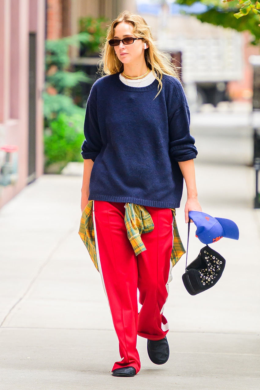 Jennifer Lawrence wearing a navy sweater, red track pants, studded bag, and flat mules in NYC