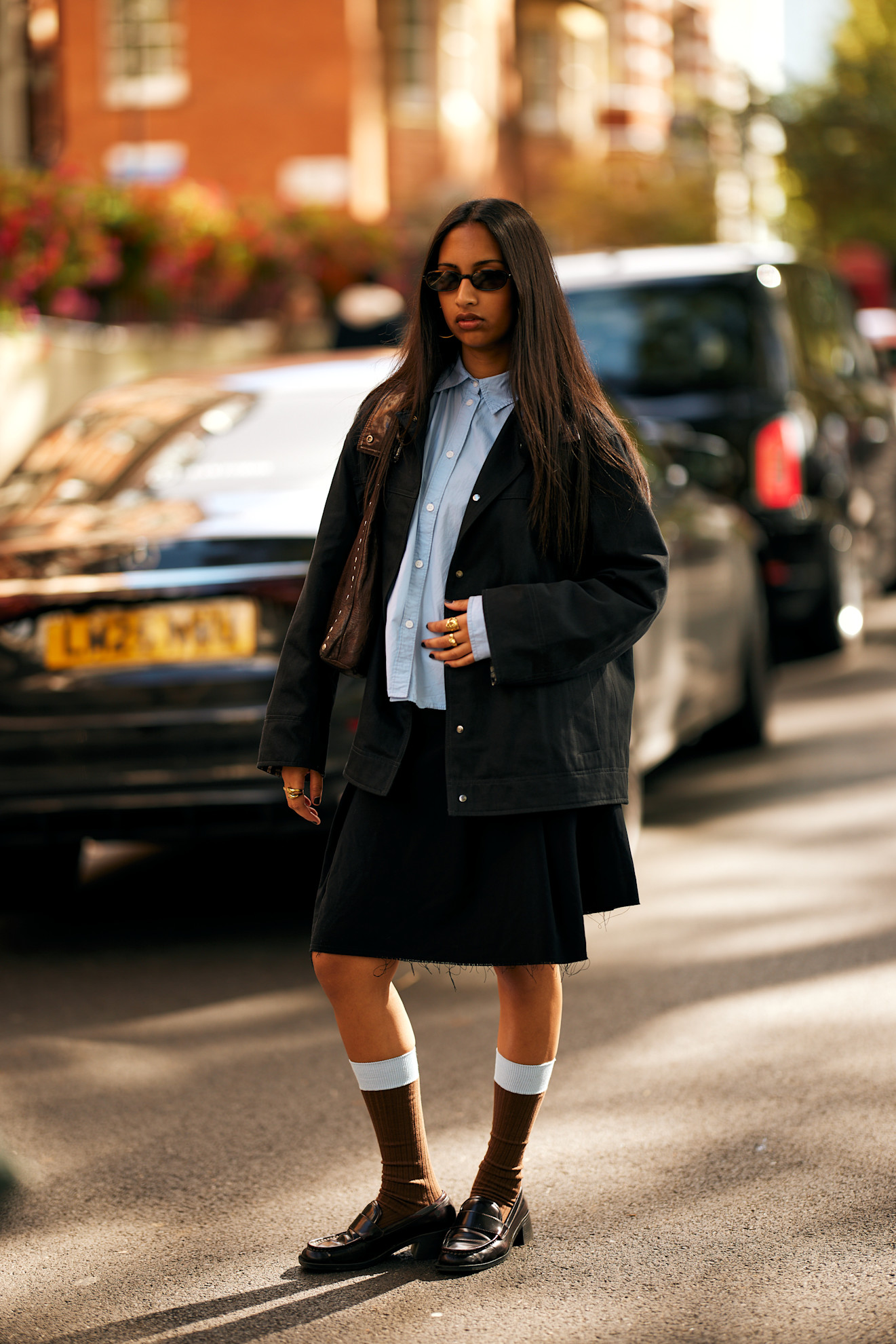 A woman in London wears a skirt with socks and loafers.