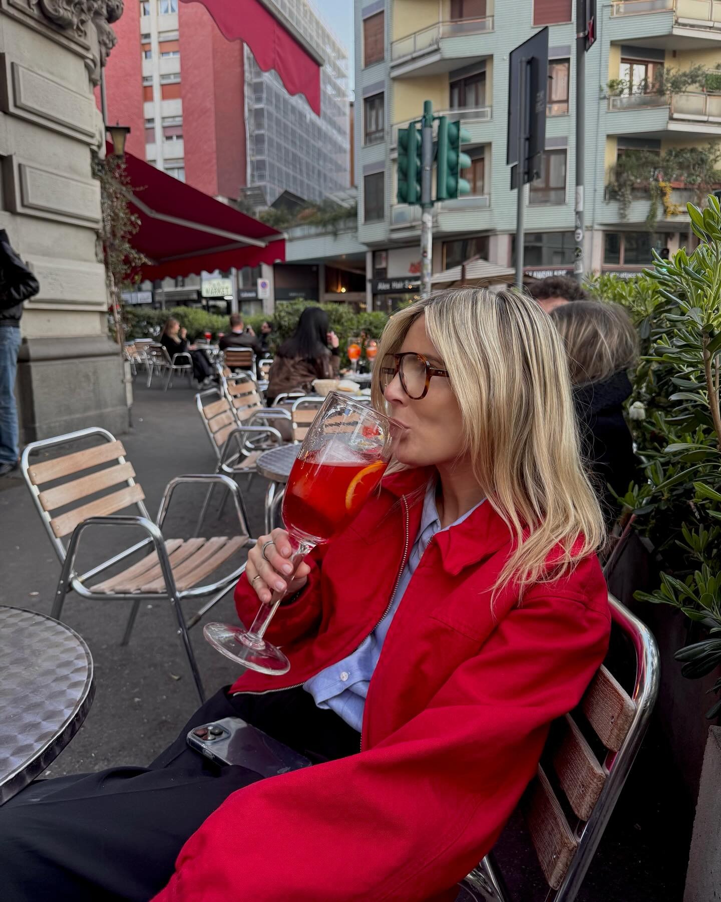 Influencer @lucywilliams02 sits down outside wearing a red jacket over a blue shirt with navy trousers.