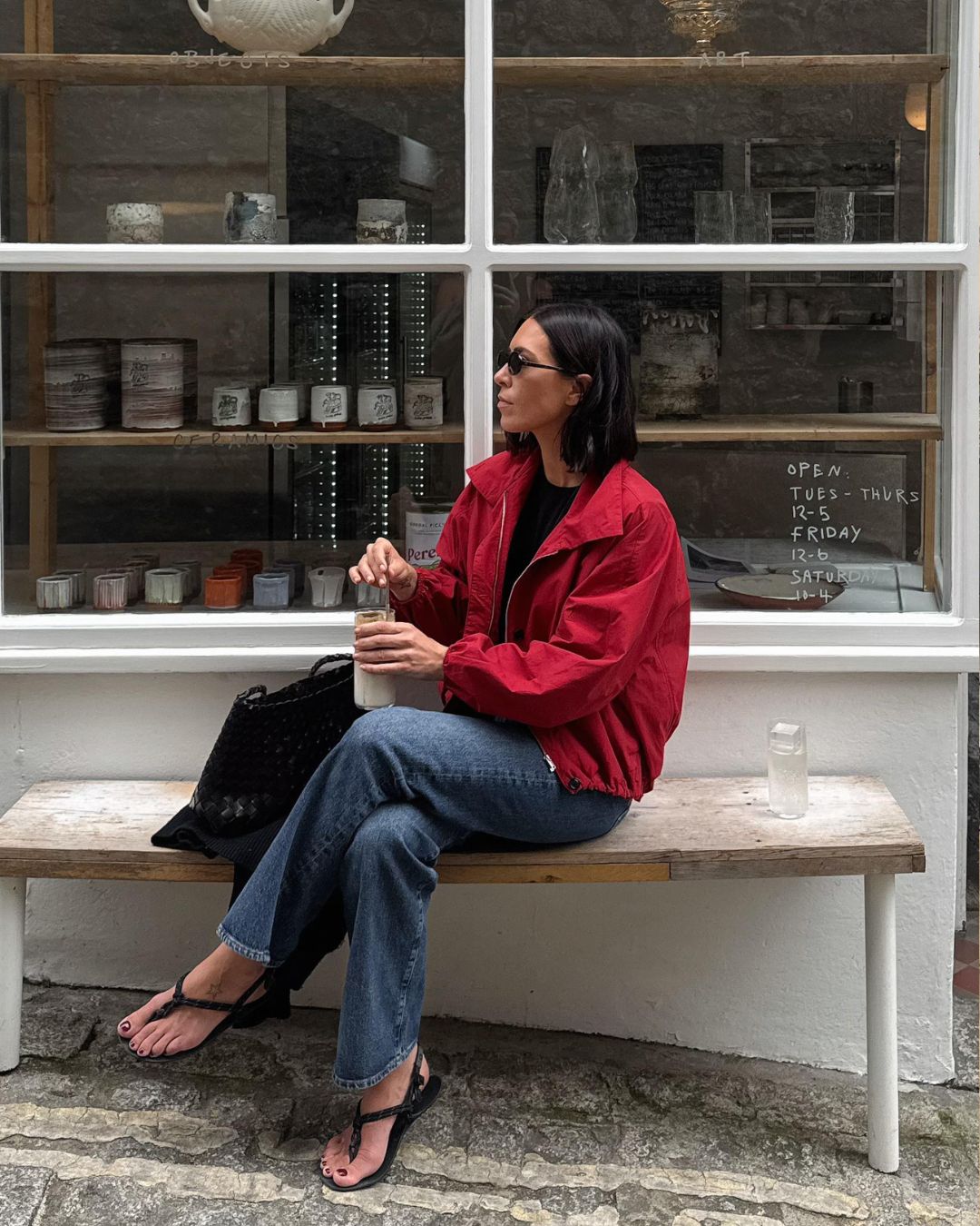 Influencer @_jessicaskye wear a red jacket with blue jeans and black sandals.