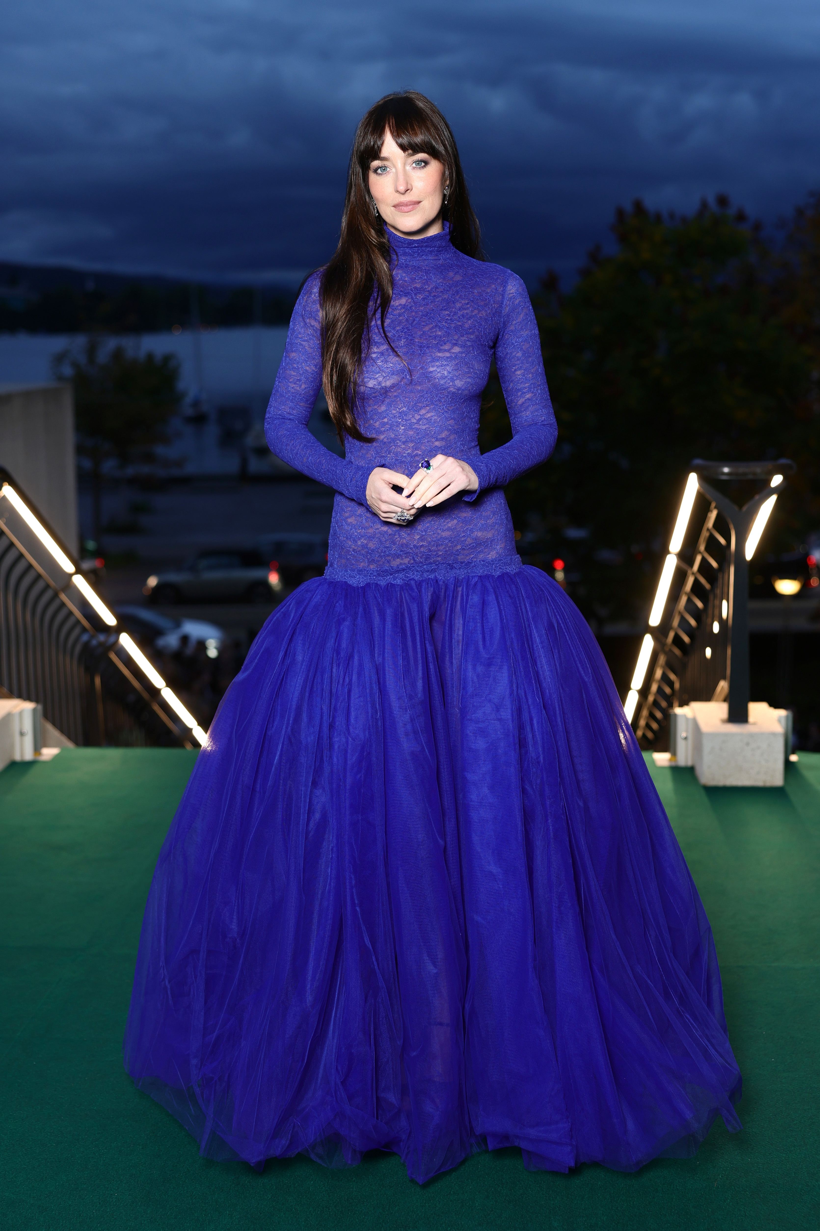 Dakota Johnson wears a bright blue gown on the red carpet in Zurich, featuring a drop waist silhouette and a sheer lace bodice