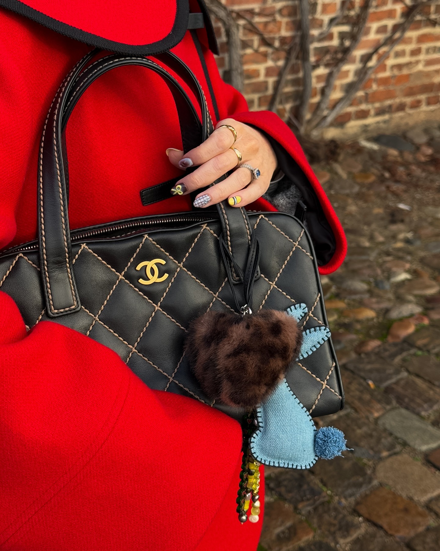 A woman holding a Chanel handbag with blue and brown nail art