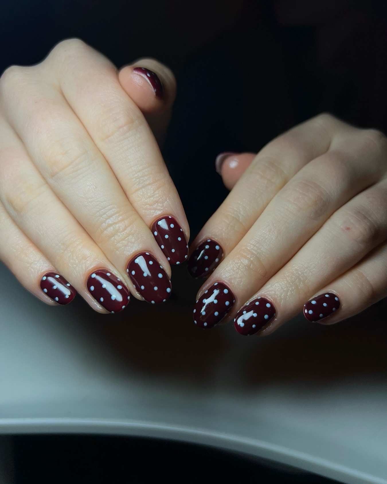 A chocolate brown manicure with blue polka dots