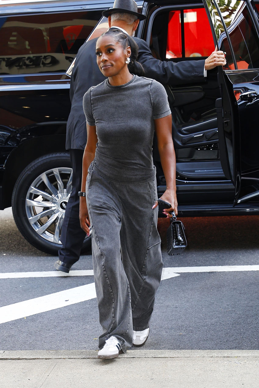 Issa Rae wearing a gray T-shirt, gray pants, and white Adidas Samba sneakers.