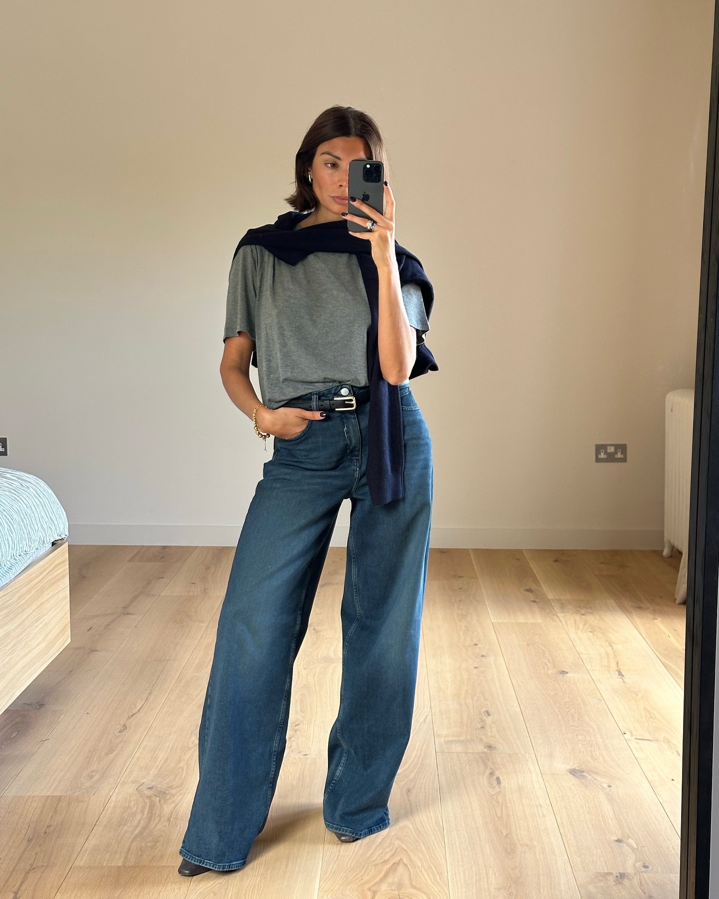 An image of @smythsisters wearing wide-leg trousers with a grey t-shirt and a navy sweater.