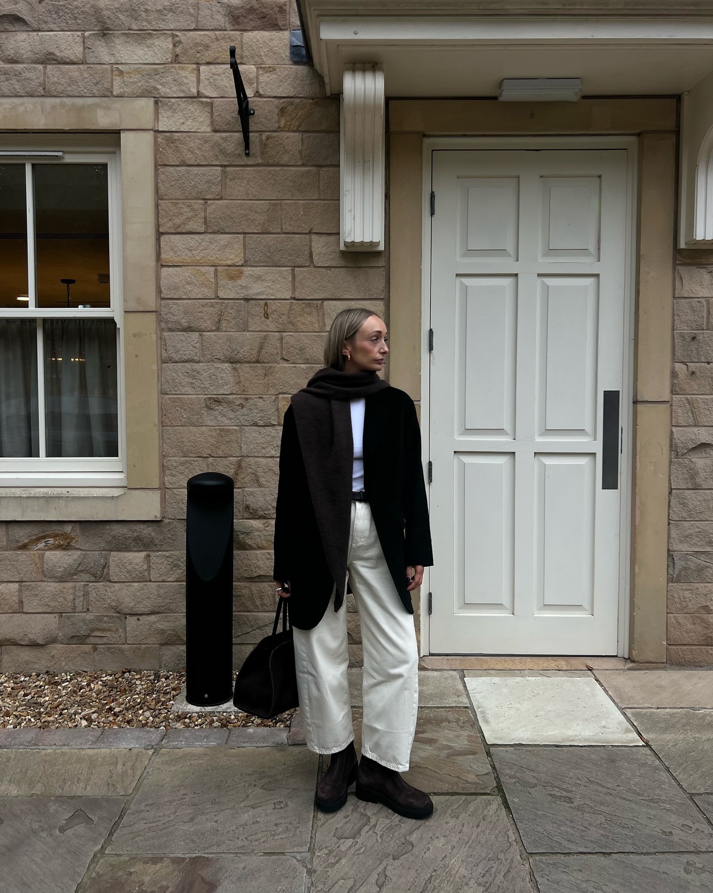 Stylist Danielle Ward wears M&amp;amp;S white jeans and brown suede boots posing against a doorway in autumn
