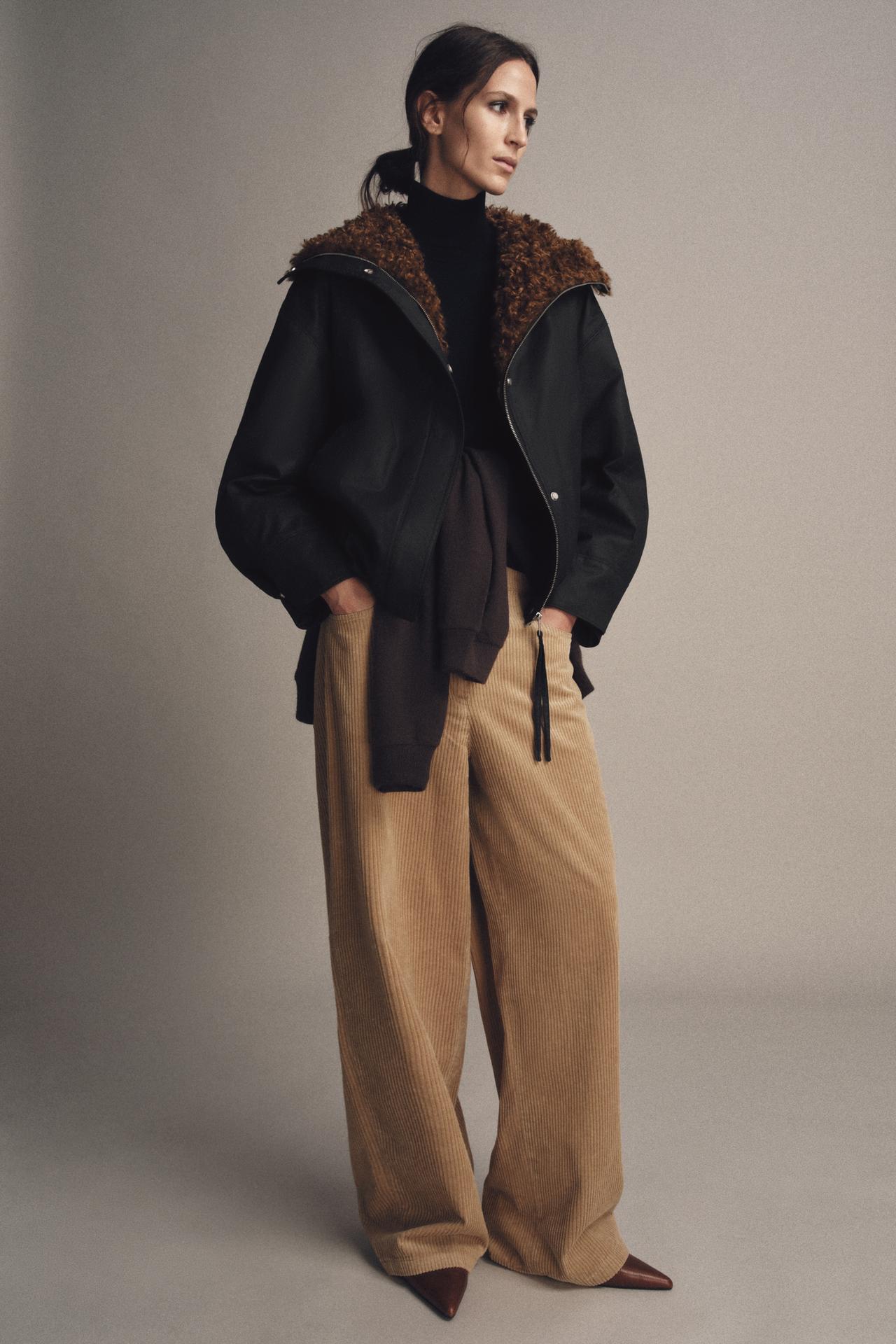 model wears fleece lined bomber jacket with corduroy pants, black turtleneck sweater, and pointed toe kitten heels with a sweatshirt around her waist
