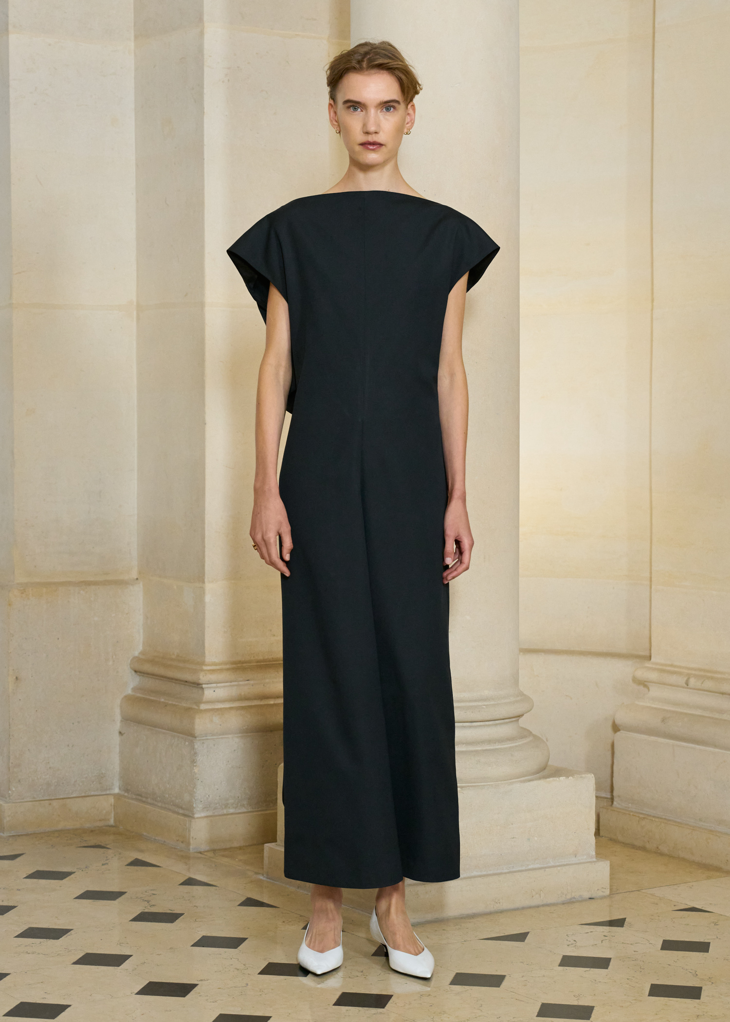 A model at the S/S 26 Carven show wearing a black long dress with white pumps.