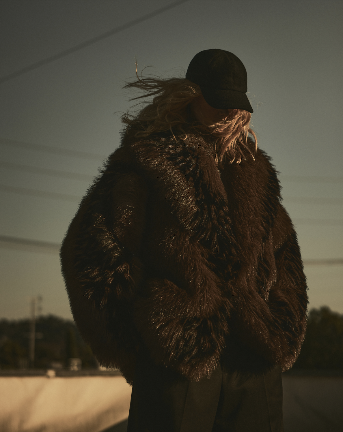 A woman wears a hat and a fur coat.