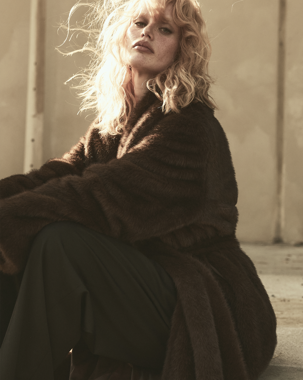 A woman wears a coat and trousers.