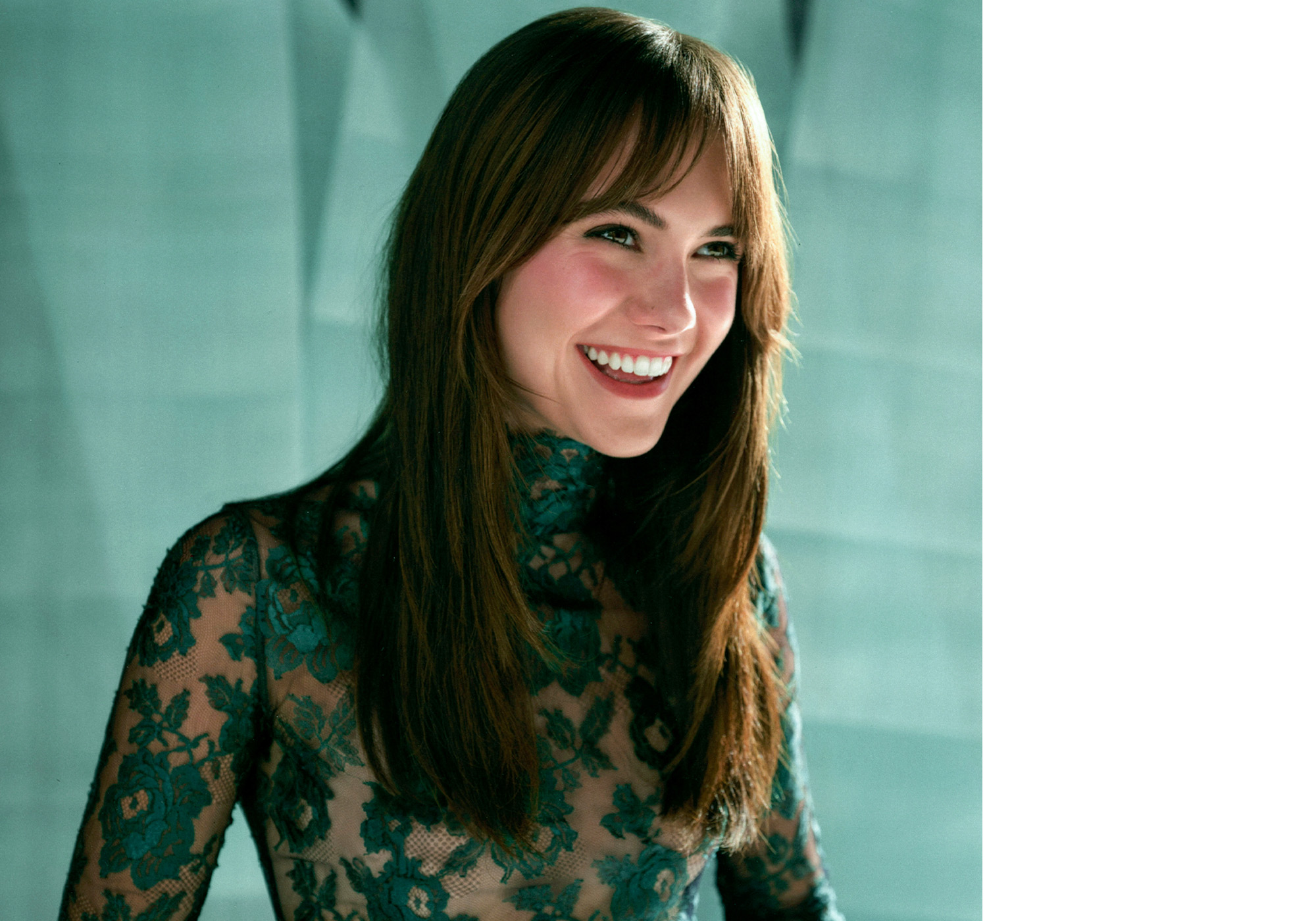 Emilia Jones for WWW&#039;s fall Ones to Watch portfolio. She is smiling while looking off camera and wearing a sheer turtleneck top with green lace detailing.