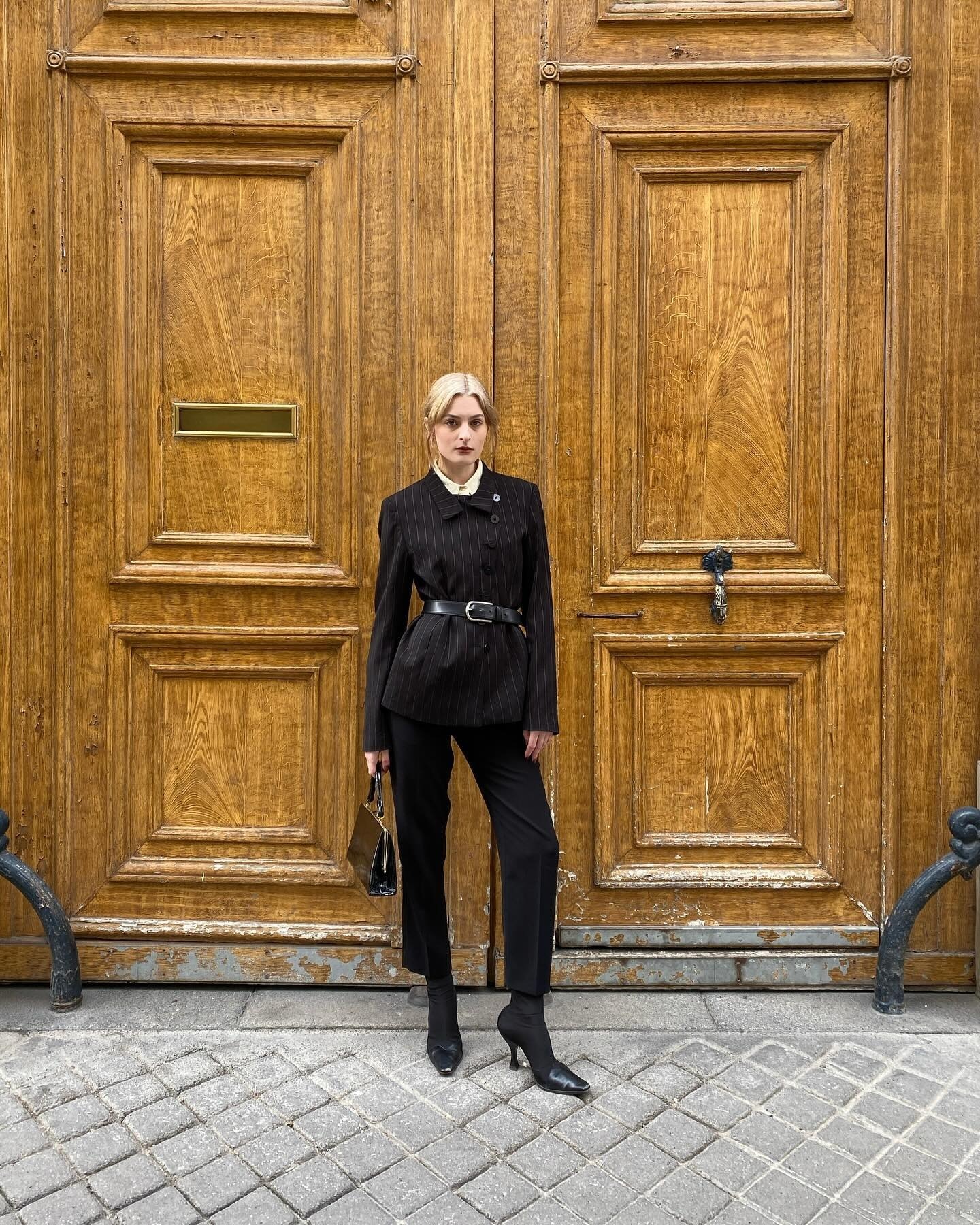 An influencer wears a long coat with jeans and heeled sock boots.