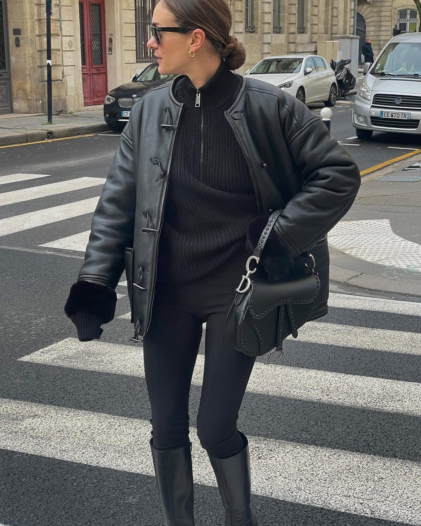 Influencer @annelauremais wears black leggings with knee-high black boots and a black leather jacket.